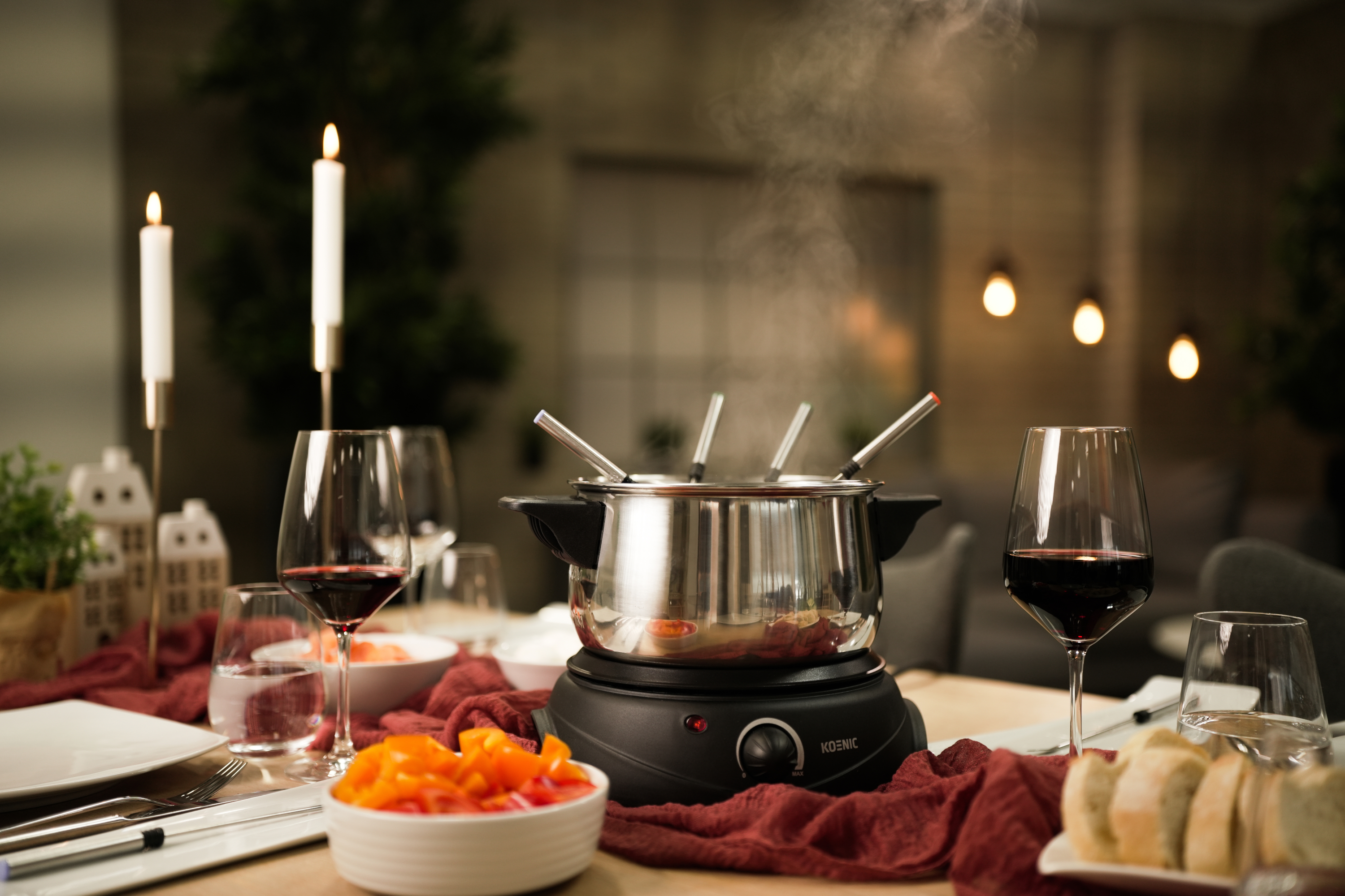 Zestaw do fondue ze świecami, kieliszkami do wina i jedzeniem, z parą unoszącą się z garnka.