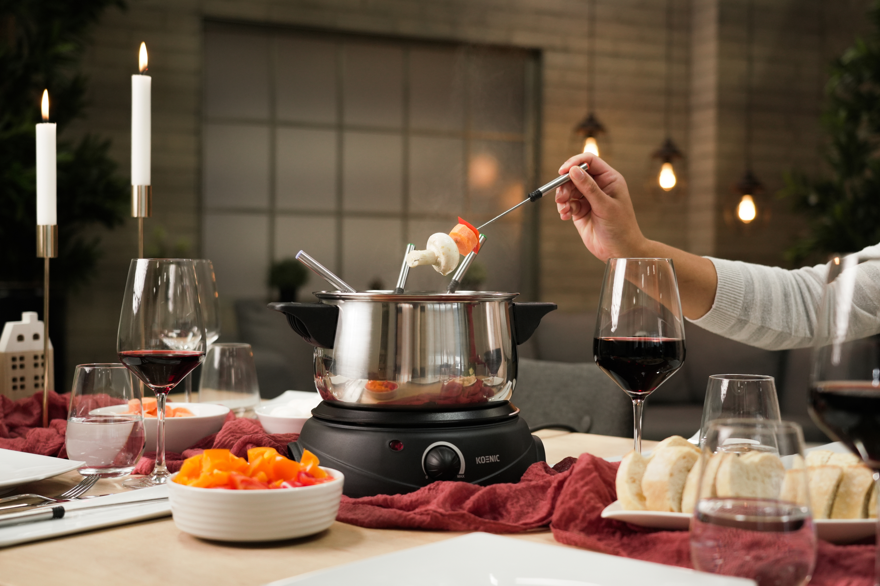 Scena z fondue z jedzeniem na widelcach nad garnkiem, świecami i kieliszkami do wina.
