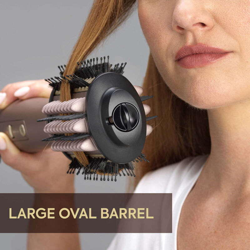 Una donna usa una spazzola per lo styling dei capelli con un grande fusto ovale per acconciare i suoi capelli.