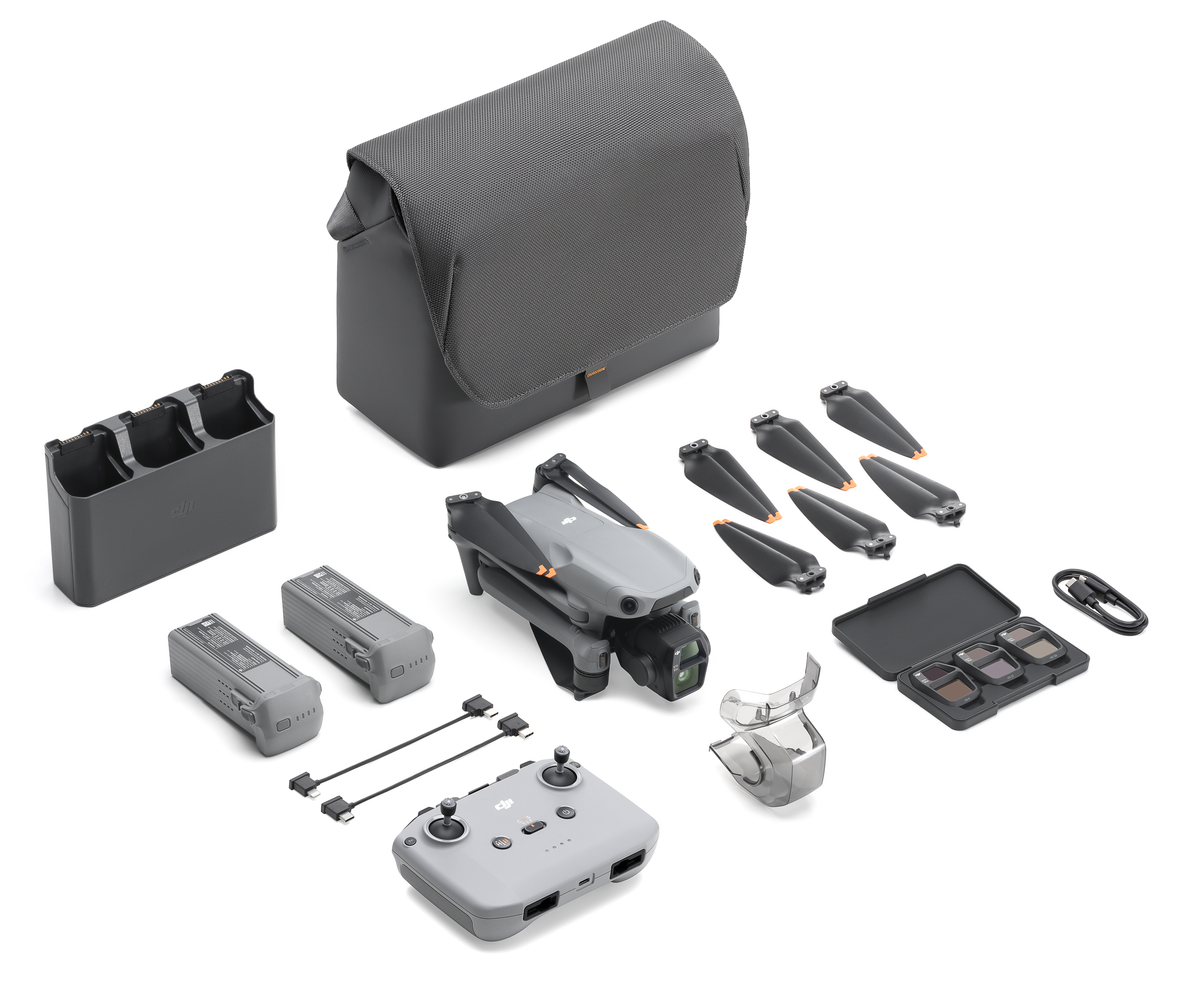 Drohnen-Kit-Layout mit Drohne, Ladegerät, Batterien, Propellern, Fernbedienung und Tragetasche. Weißer Hintergrund.