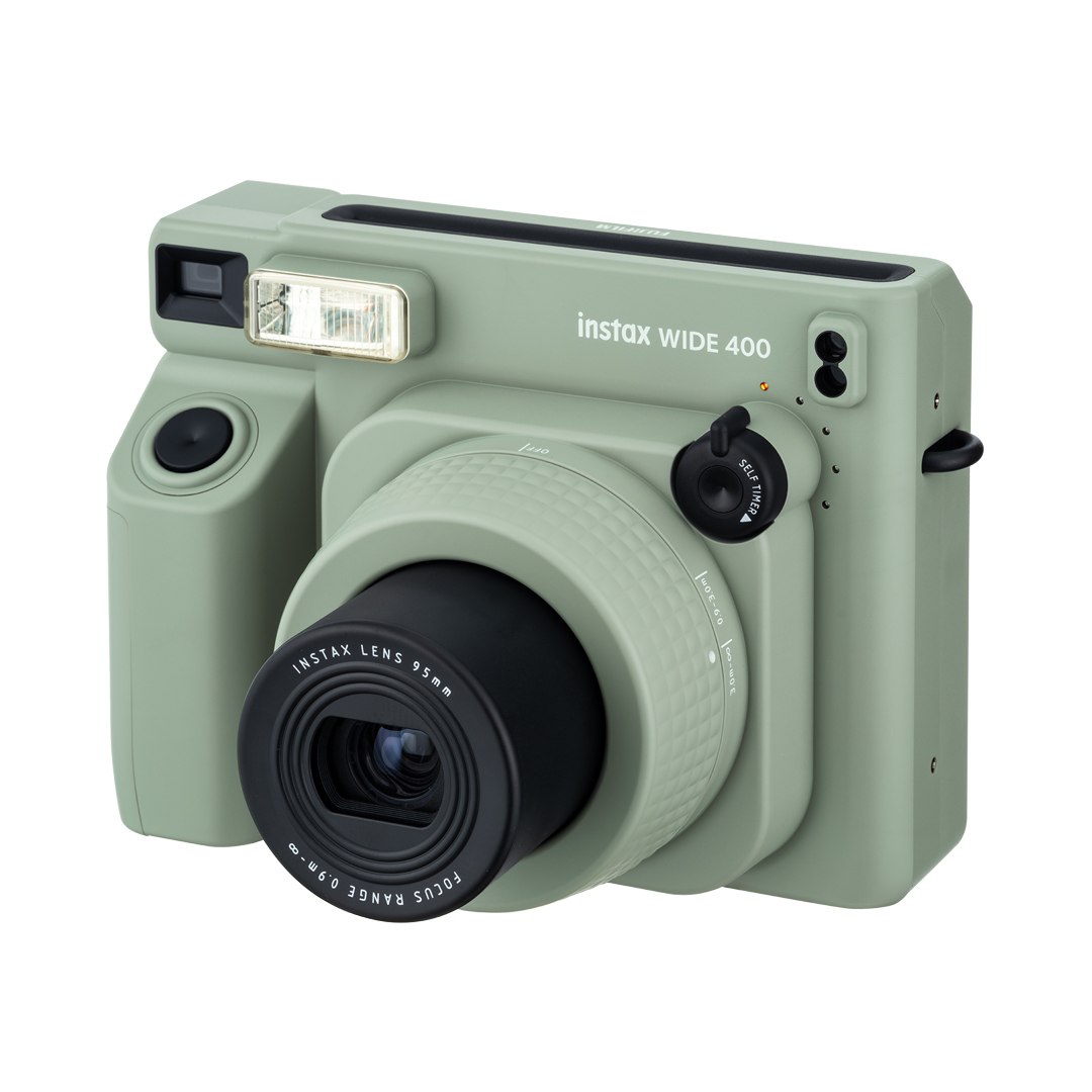 Yeşil Instax Wide 400 kamera. Siyah lens, flaş ve kadranlar. Beyaz zemin.