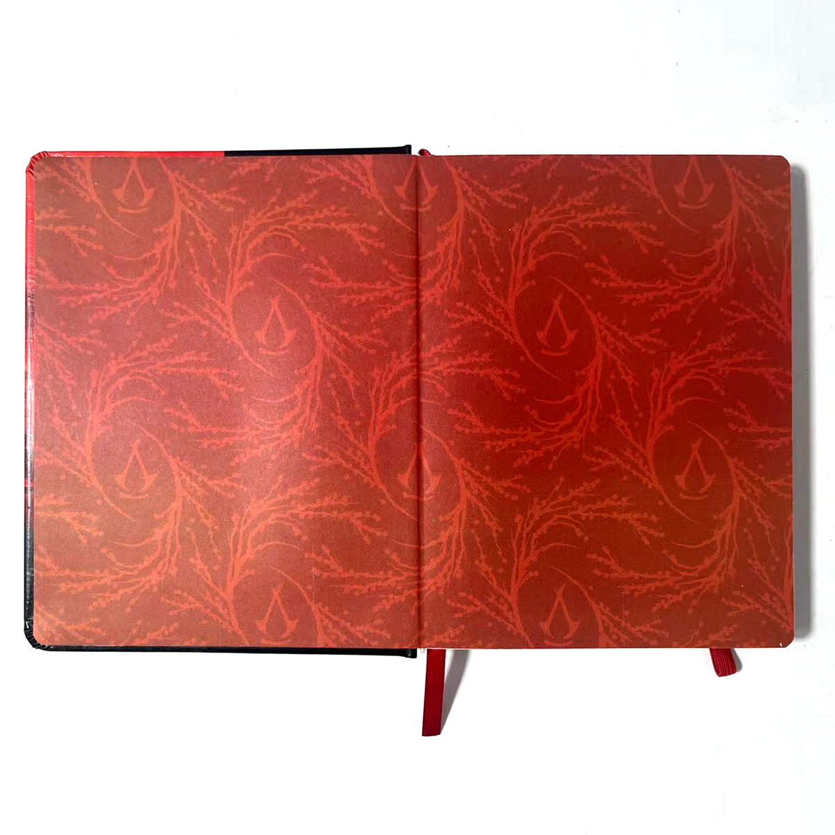 Offenes Notizbuch. Die Seiten zeigen ein rotes Muster aus Ästen und Blättern mit einem Wassertropfen-Logo.