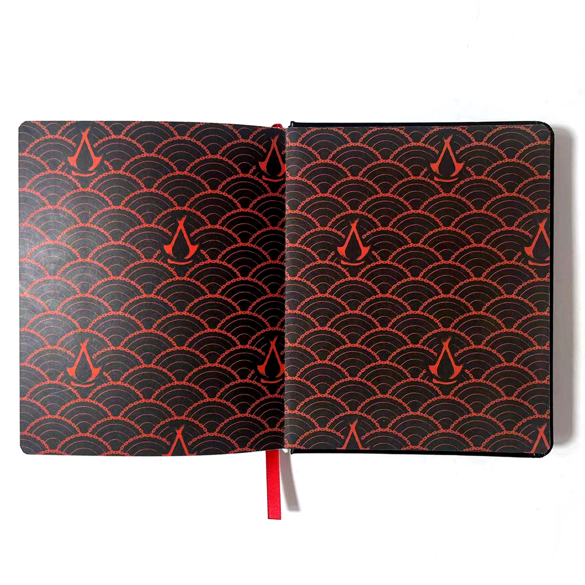 Offenes Notizbuch mit rotem und schwarzem Design. Das Muster zeigt Assassin's Creed-Symbole.