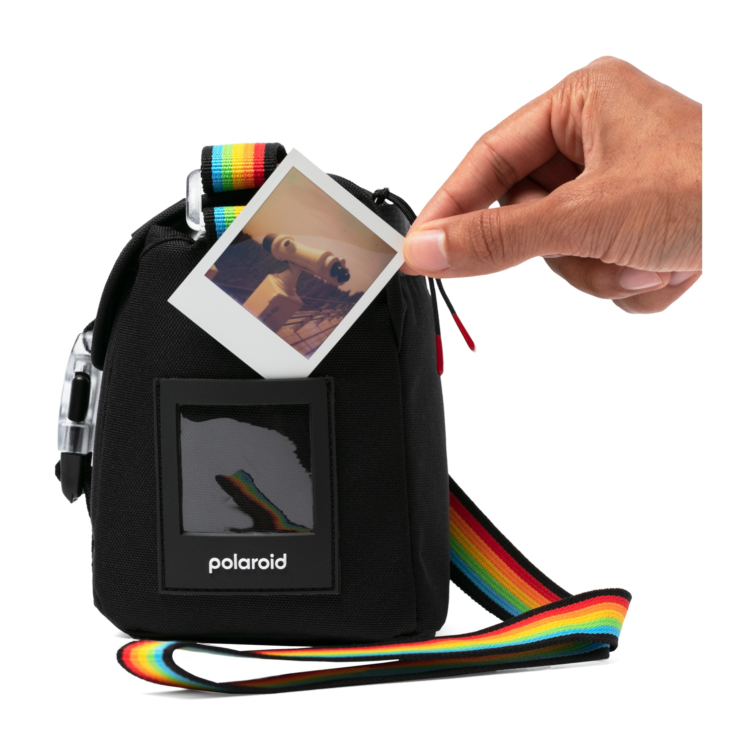 Borsa Polaroid nera con cinturino arcobaleno, una mano tiene una foto di un telescopio, sfondo bianco.