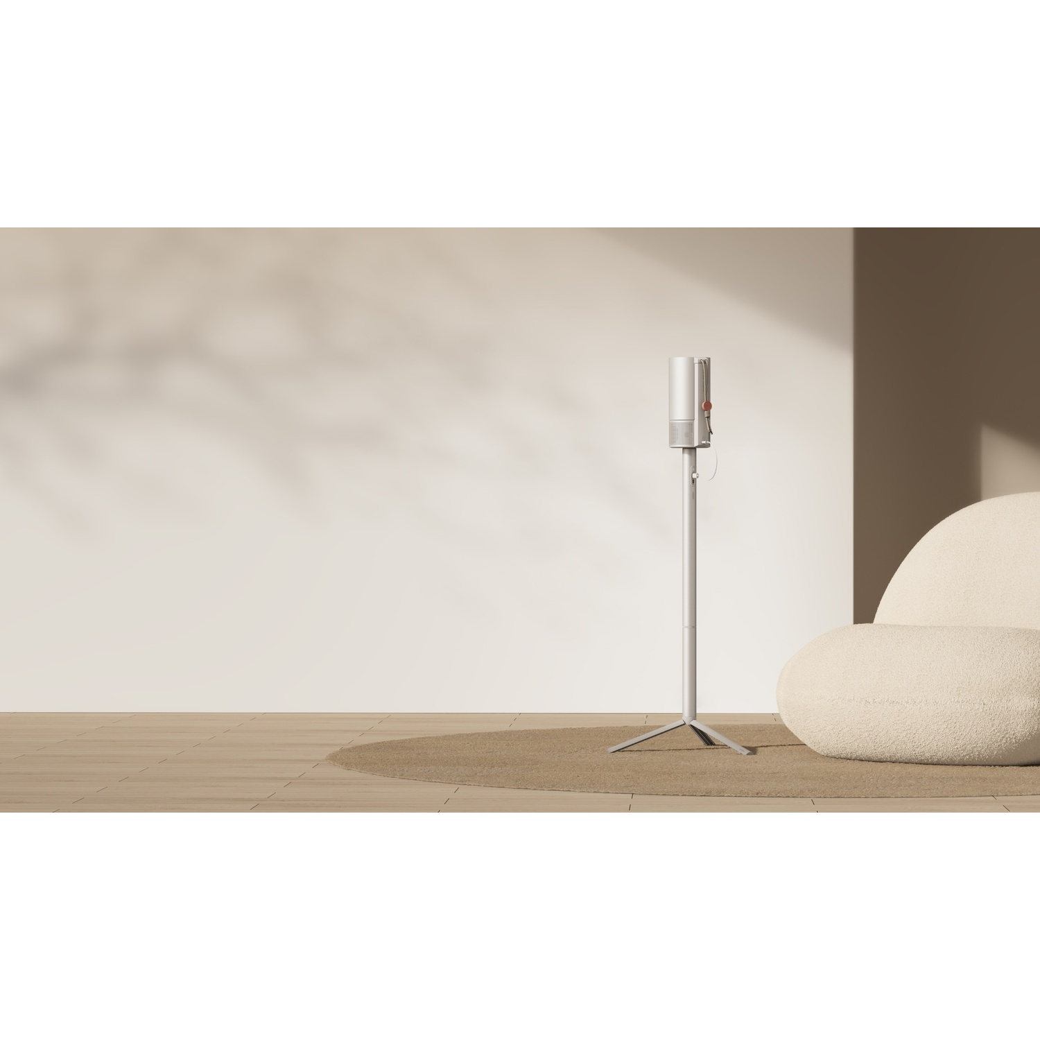 Un aspirapolvere verticale bianco su un supporto, con una sedia e un tappeto sullo sfondo.
