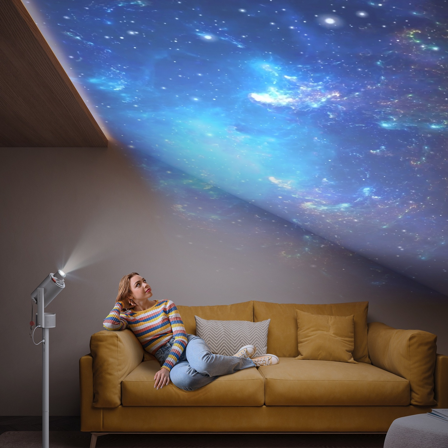 Una donna su un divano giallo guarda un cielo stellato proiettato da un proiettore.