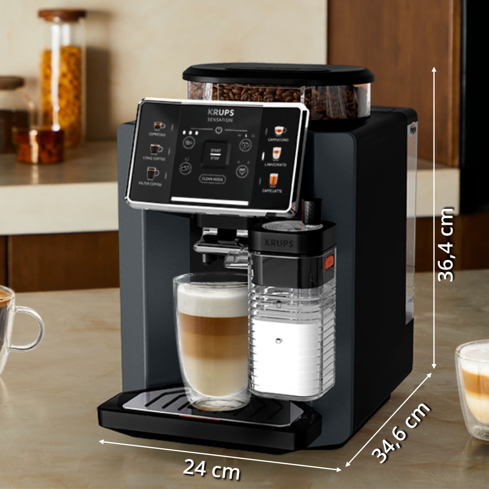 Máquina de café Krups negra con latte en vaso. Dimensiones etiquetadas. Granos de café visibles arriba.
