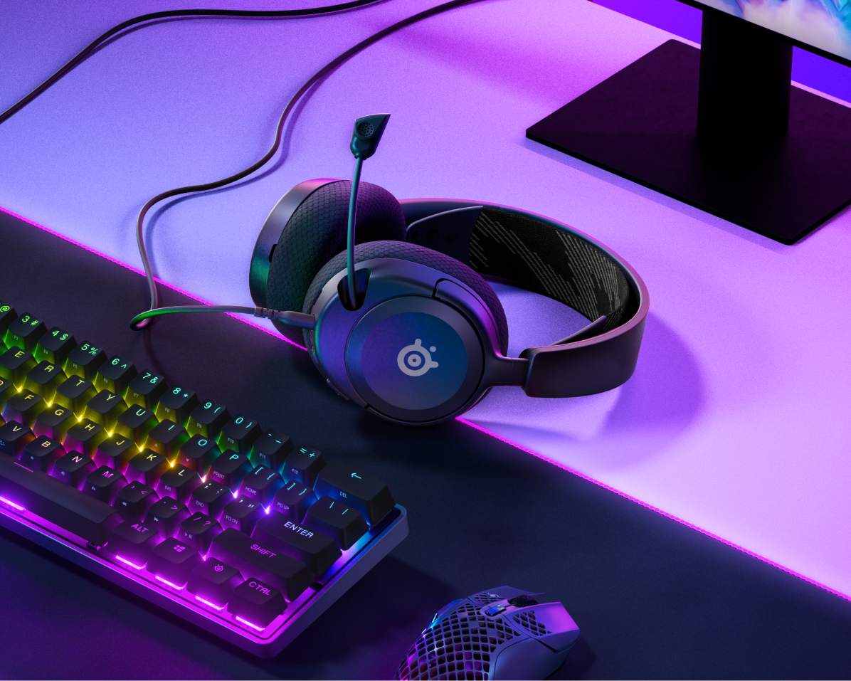 Un'impostazione di gioco con tastiera, mouse, cuffie e monitor su una scrivania.