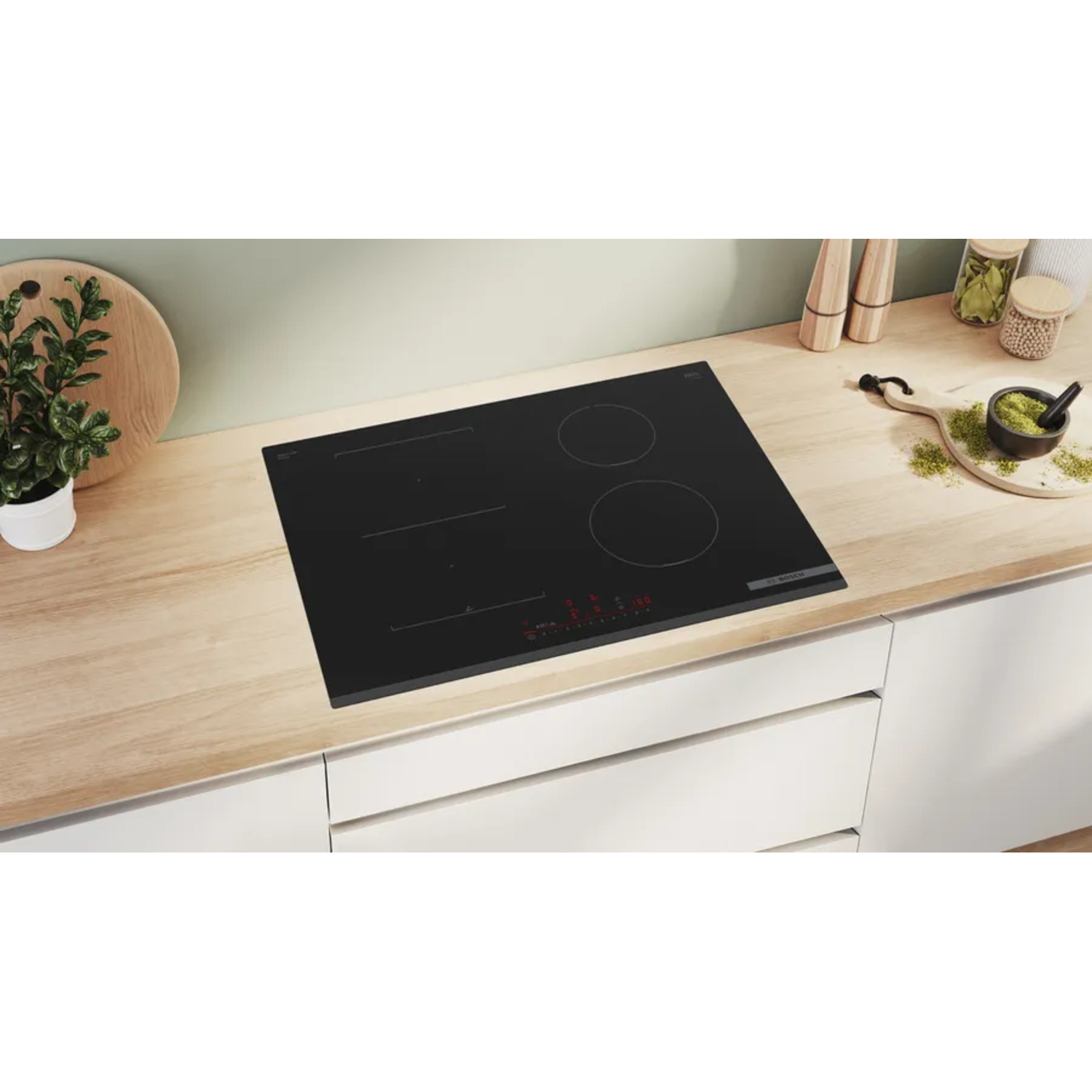 Table de cuisson électrique noire avec trois brûleurs, sur un comptoir en bois clair.