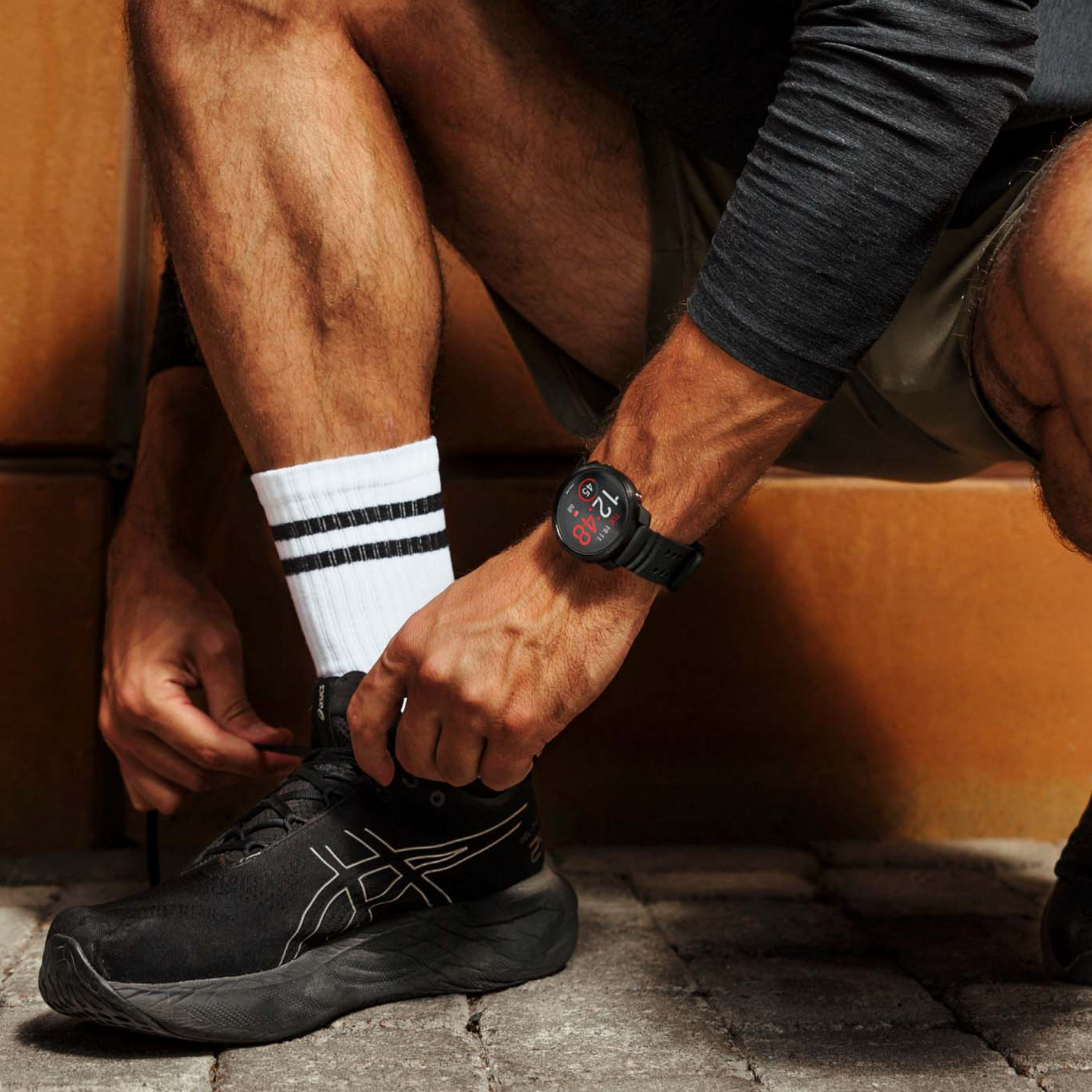 Hombre atándose el zapato, usando un reloj inteligente.