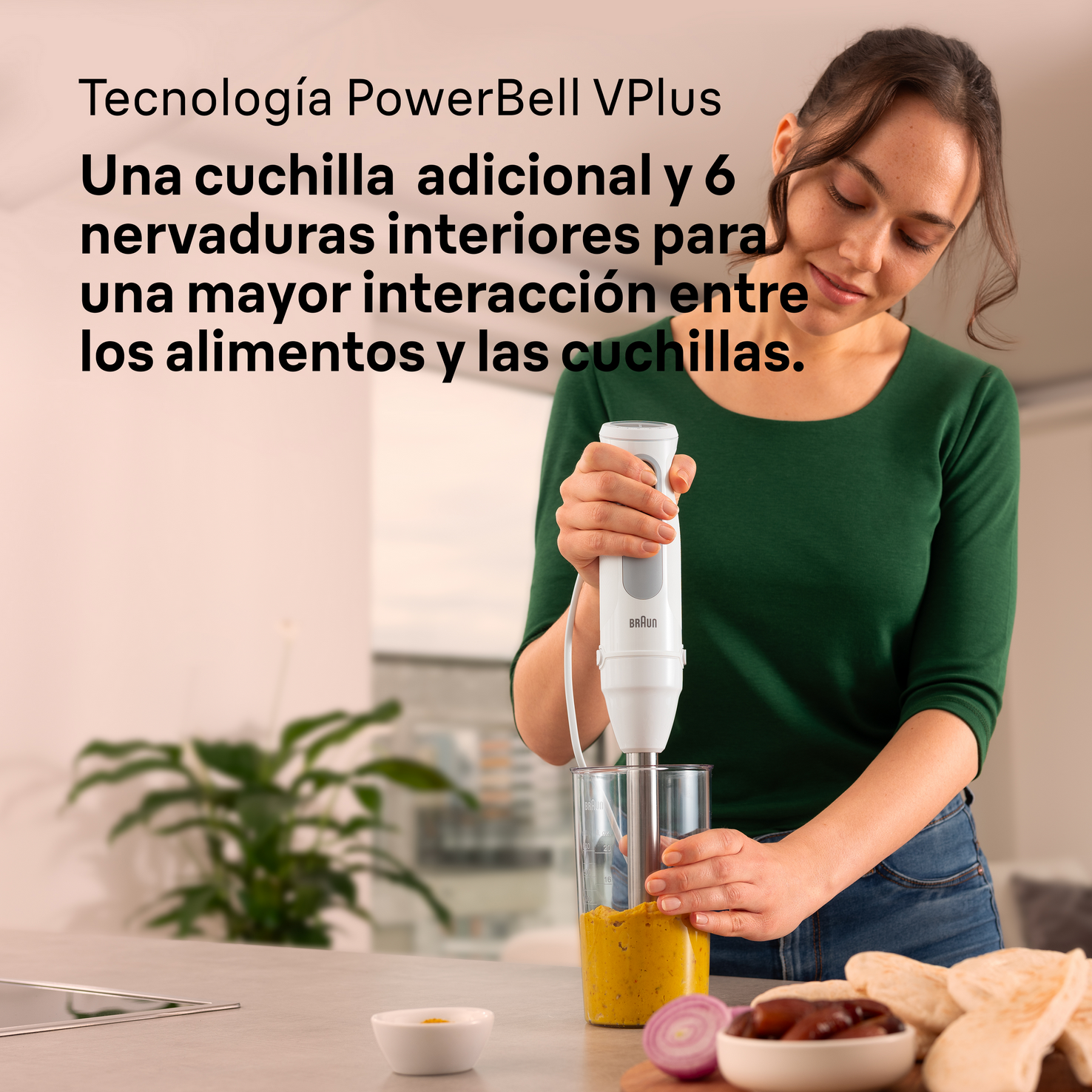 Una mujer está usando una batidora de mano, mezclando contenido en un vaso. Los ingredientes están en la mesa.