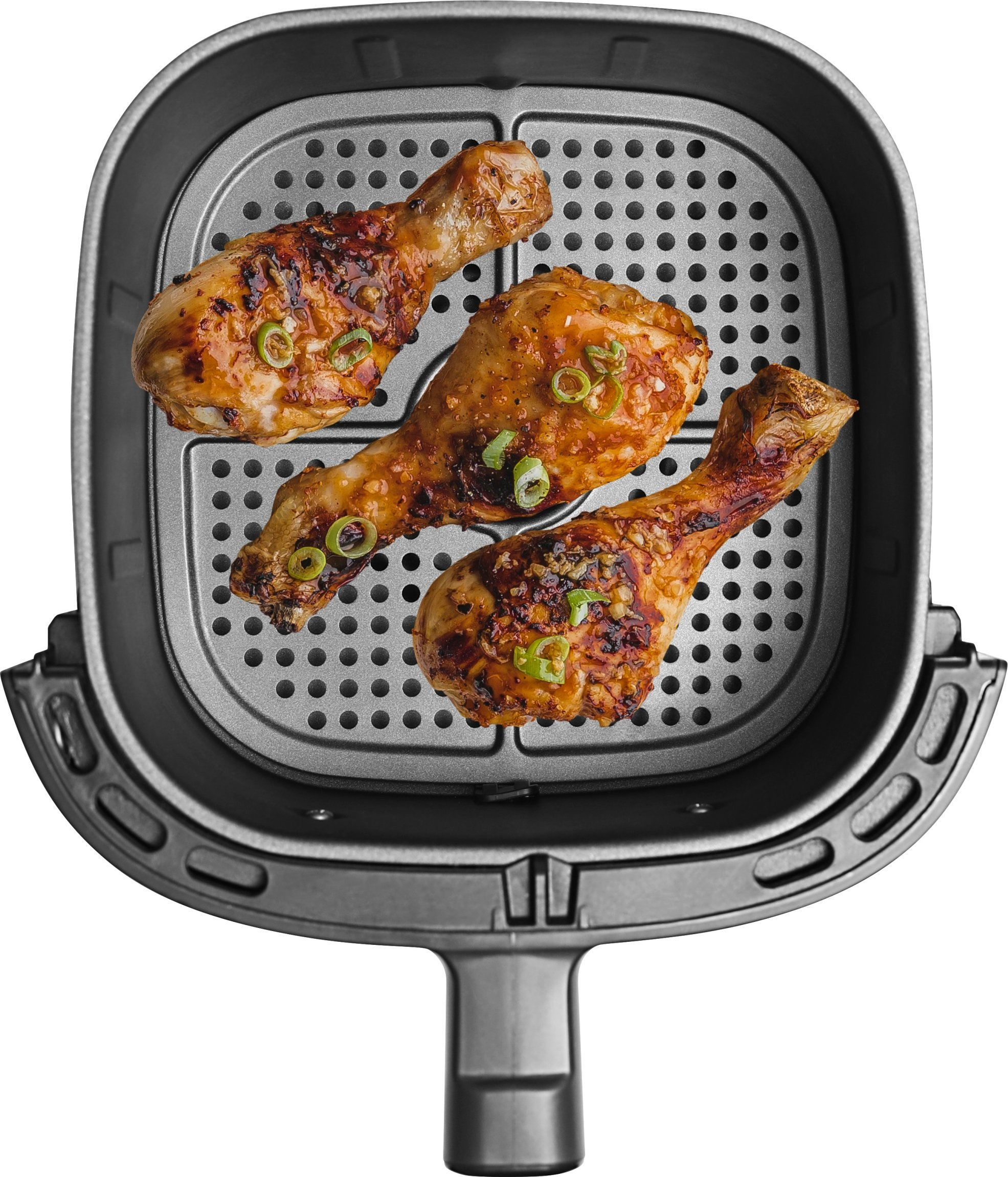 Widok z góry na kosz do frytkownicy powietrznej z trzema ugotowanymi pałkami z kurczaka.