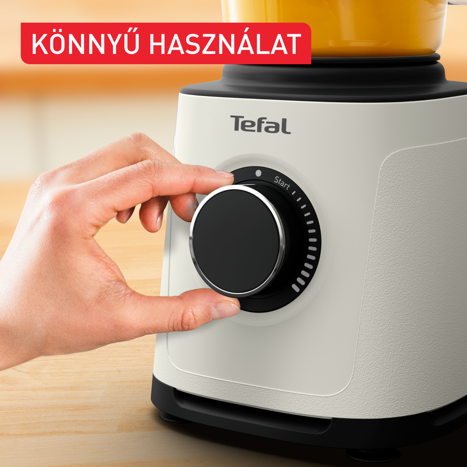 Egy kéz egy tárcsát forgat egy fekete-fehér konyhai robotgépen.