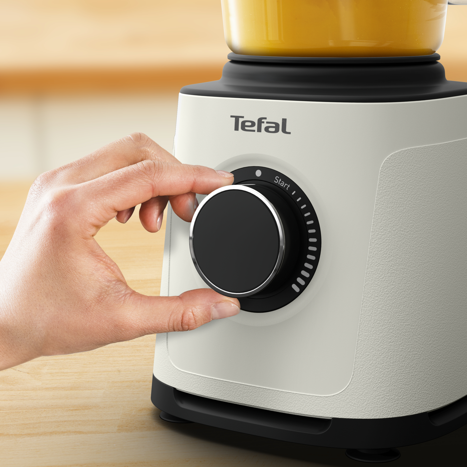 Egy kéz a fehér-fekete Tefal turmixgép tárcsáját forgatja, egy start jelzővel.