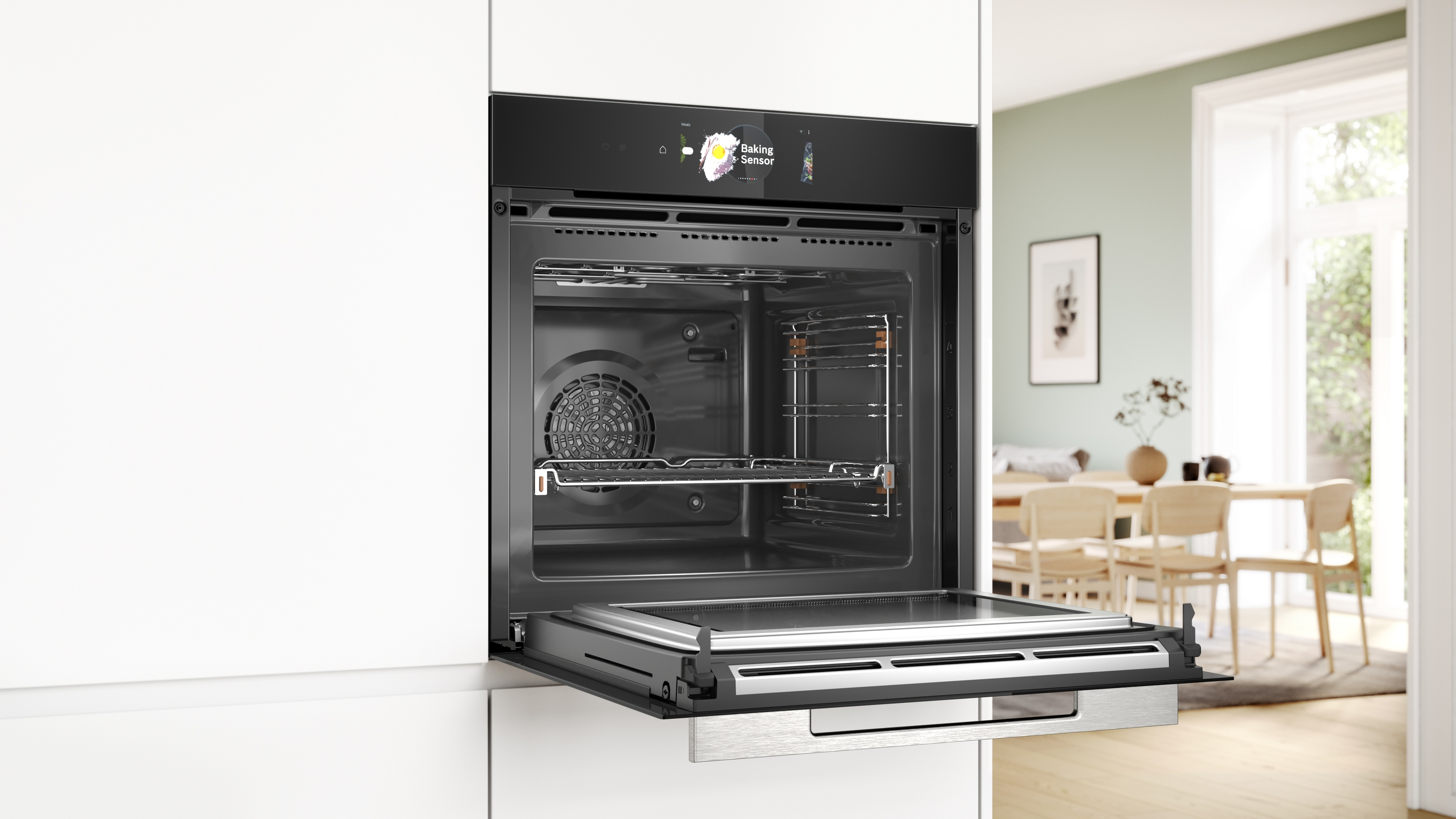 Ein geöffneter Backofen mit ausgezogenem Blech, vor einer Kücheneinrichtung mit einem Holztisch.