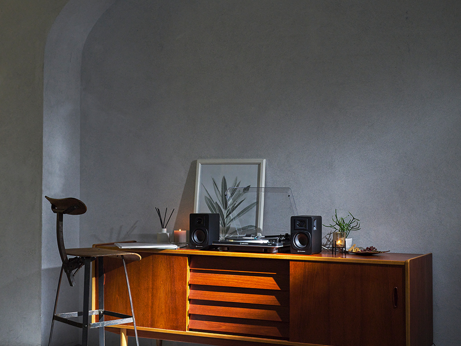 Stylizacja salonu w stylu vintage z głośnikami, gramofonem i dekoracjami na drewnianej szafce.