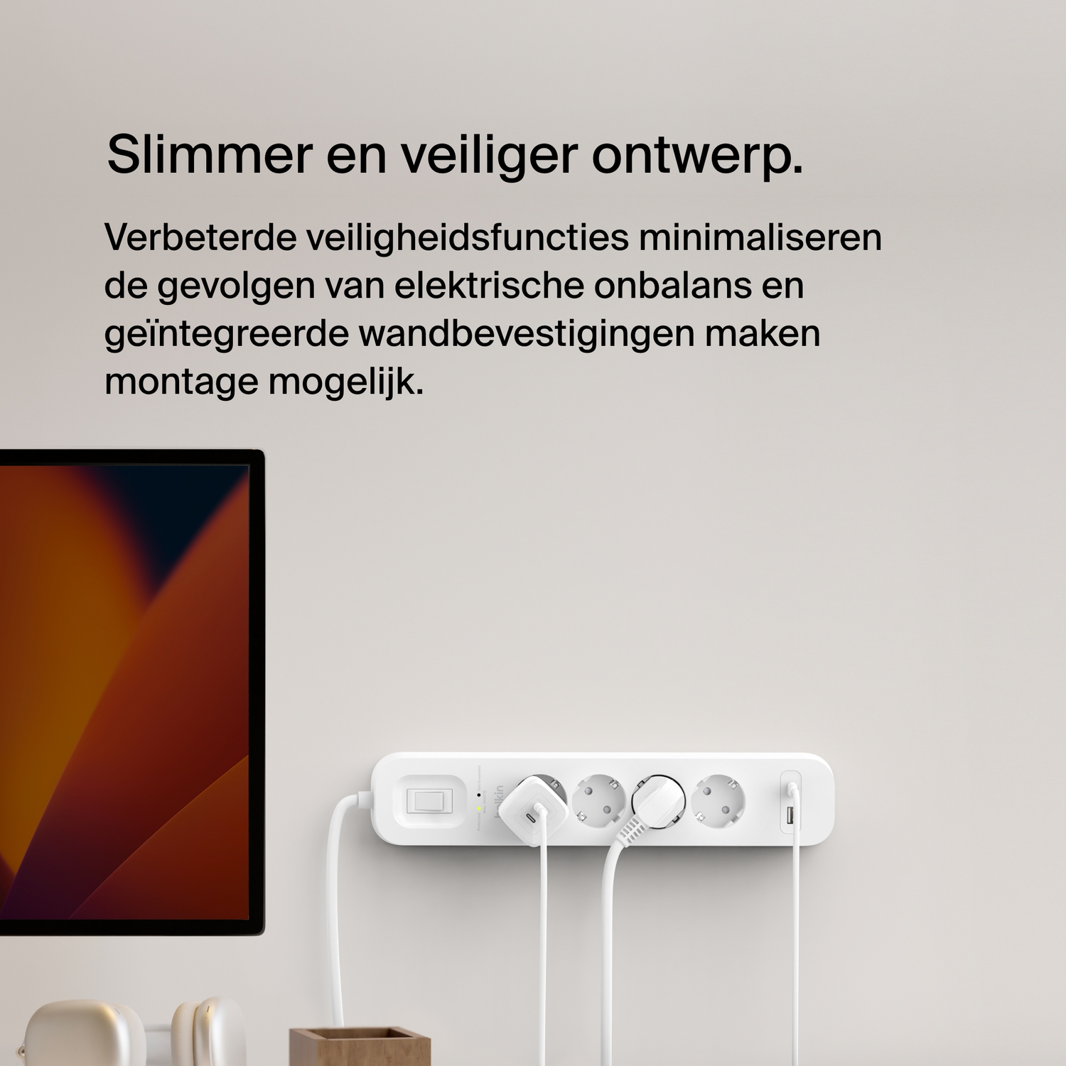 Een witte stekkerdoos met vier stopcontacten, drie stekkers en een schakelaar, aan de muur bevestigd.