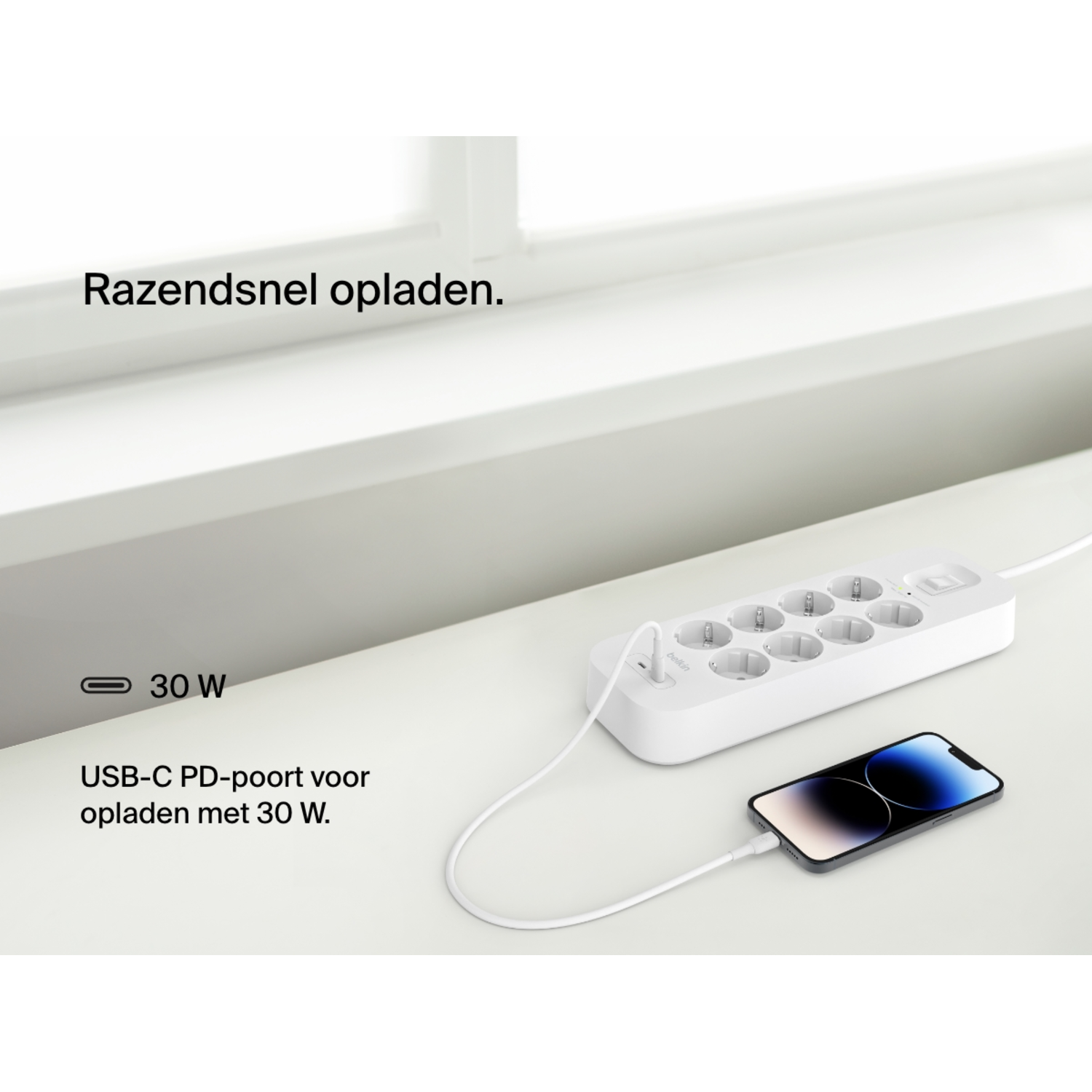 Een witte stekkerdoos met een telefoon die oplaadt, tekst vermeldt USB-C PD-poort voor 30W opladen.