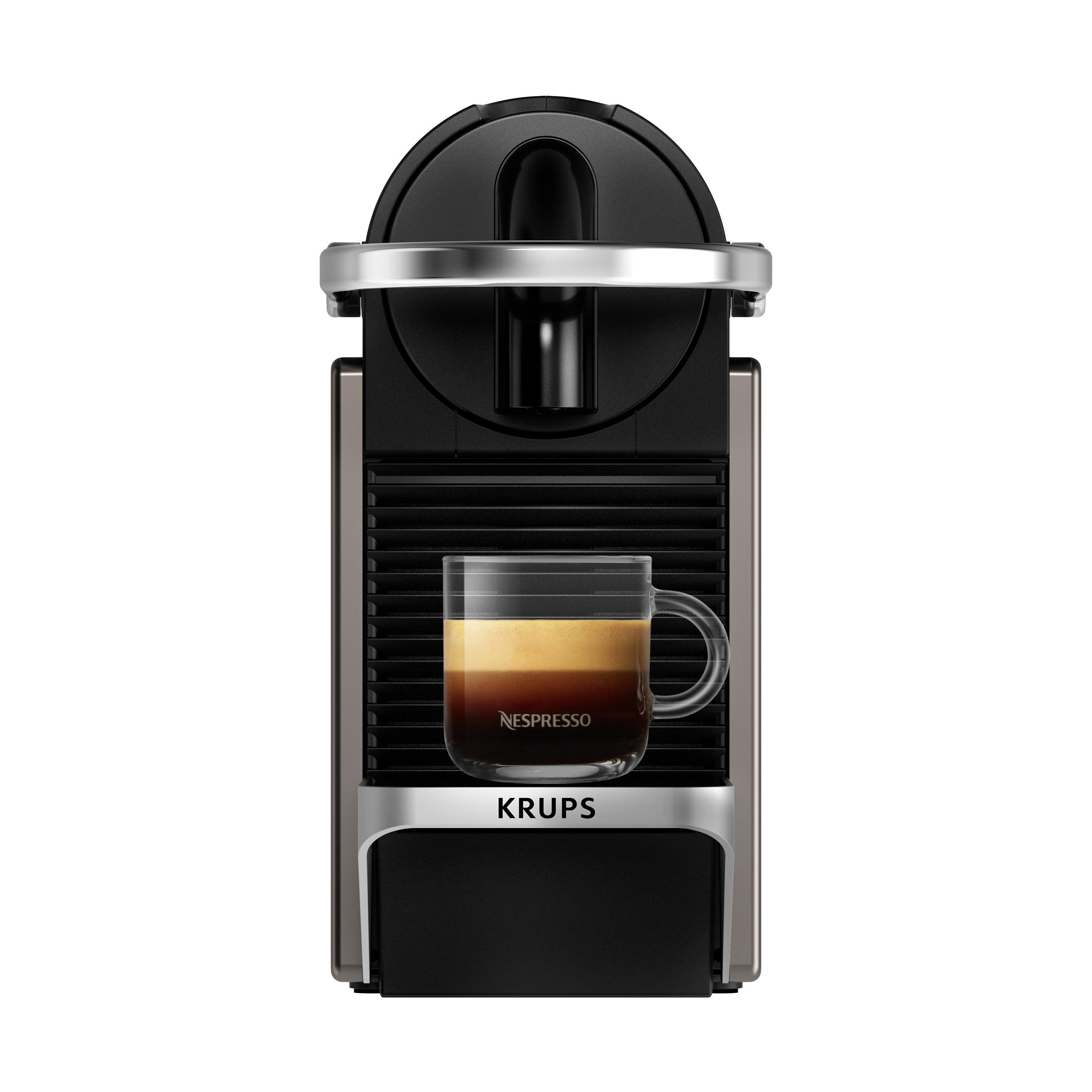 Eine Nespresso Krups Kaffeemaschine mit einer Tasse Kaffee und einem transparenten Glas.