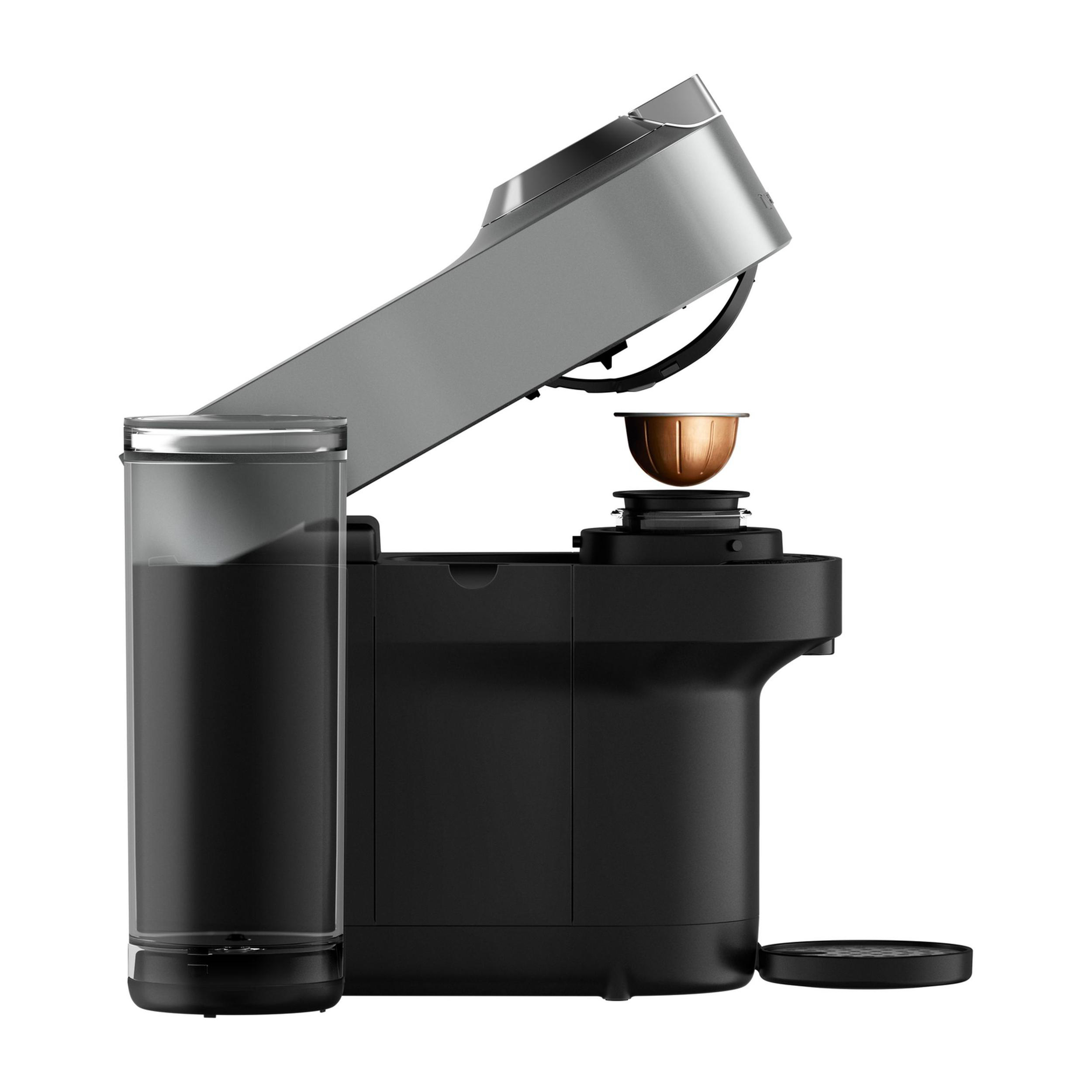 Kaffeemaschine mit offenem, grauem Deckel. Eine Kaffeepad ist eingesetzt. Ein Wassertank befindet sich links. Schwarze Basis.