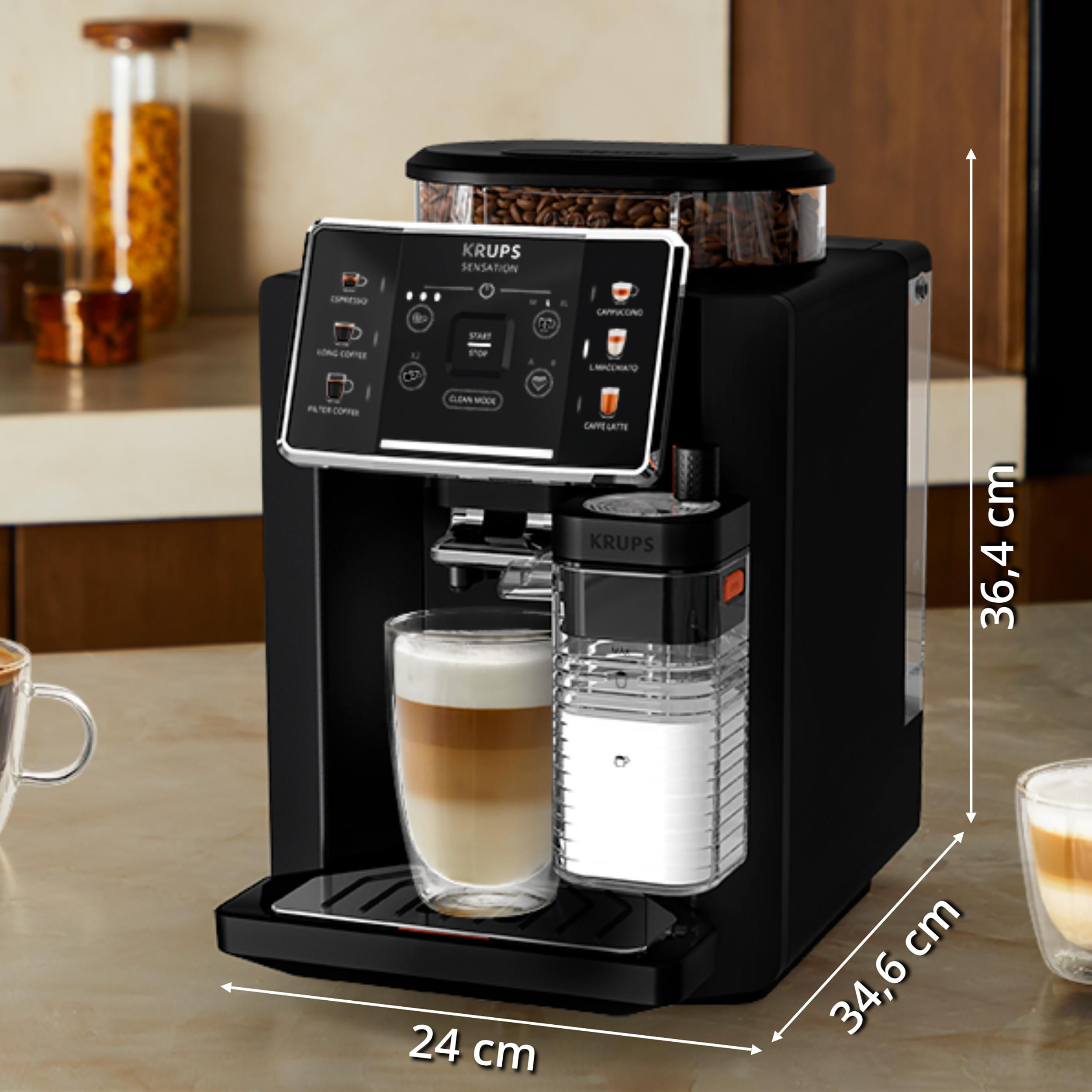 Schwarze Krups Kaffeemaschine mit Latte im Glas. Abmessungen sichtbar.