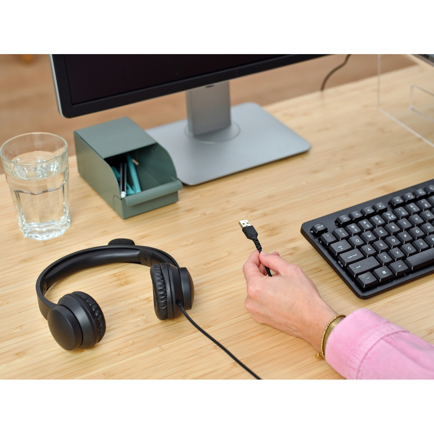 Una mano che tiene un cavo USB su una scrivania.