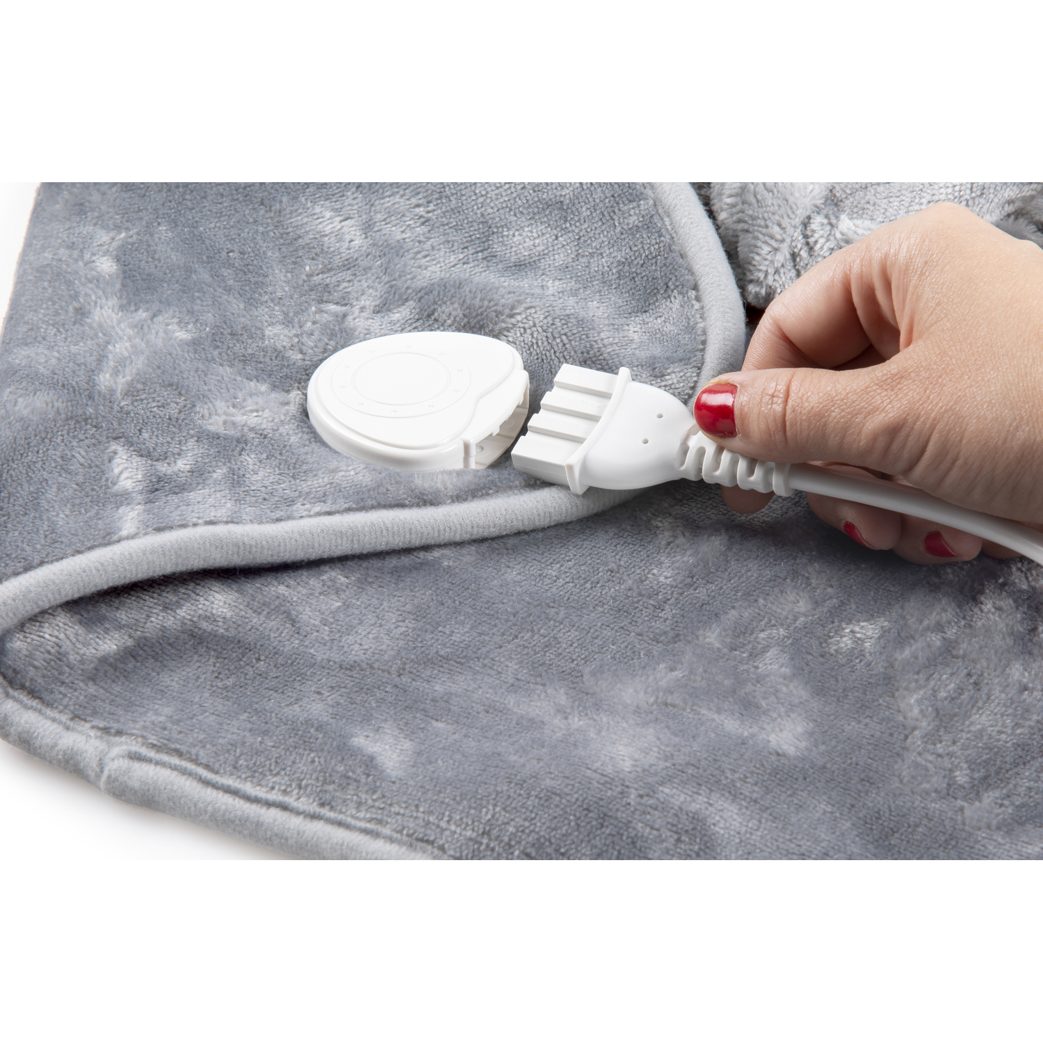 Une main branchant un cordon d'alimentation blanc dans un coussin chauffant gris et moelleux.