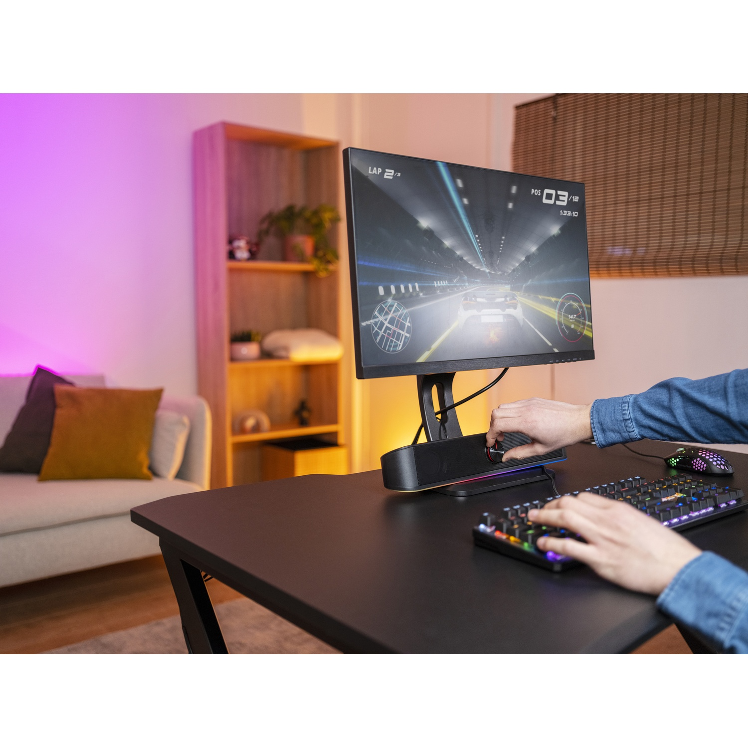 Una persona che utilizza un computer con un gioco di corse sul monitor. Sono visibili una tastiera e una scrivania.