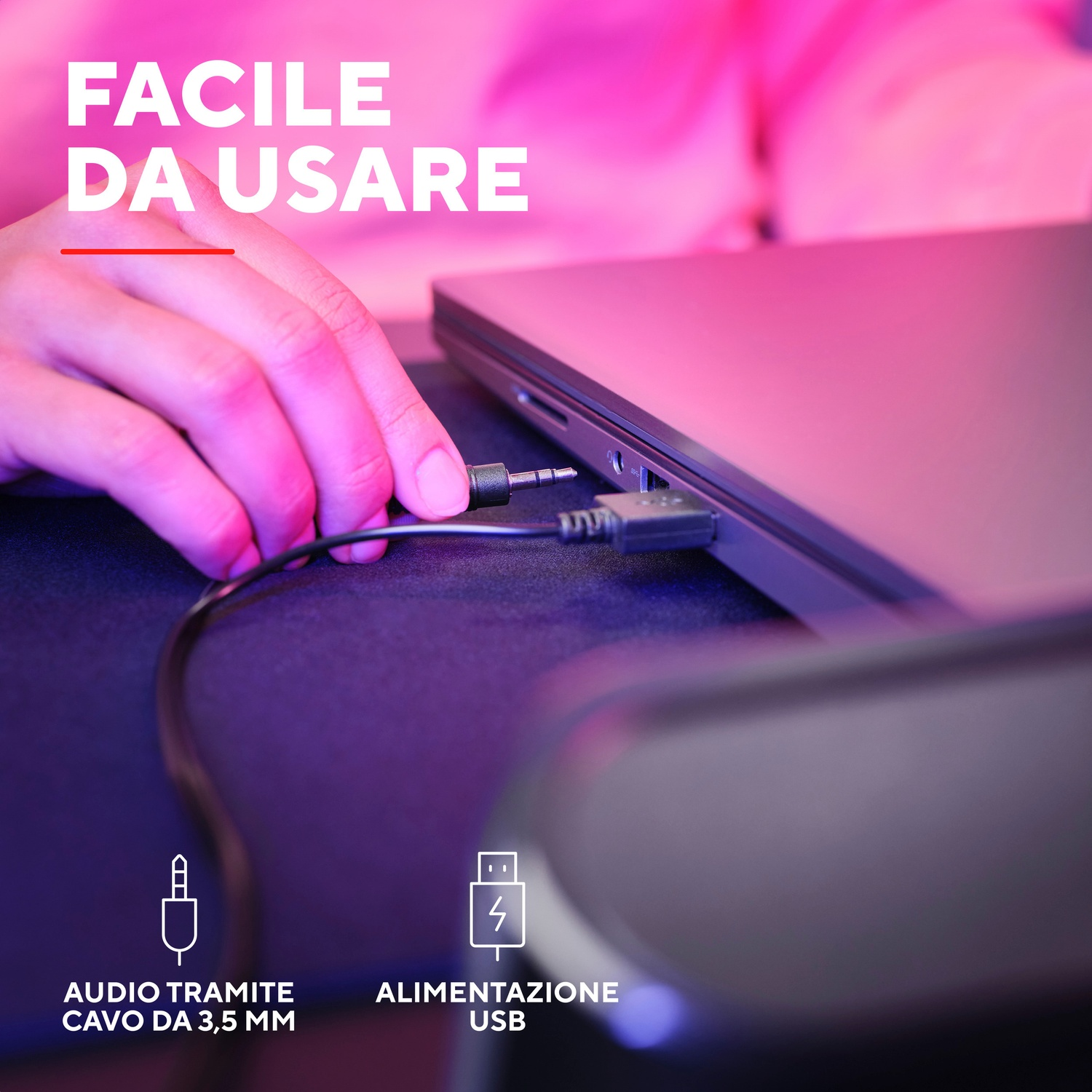 La mano collega un jack per cuffie nero a un laptop.