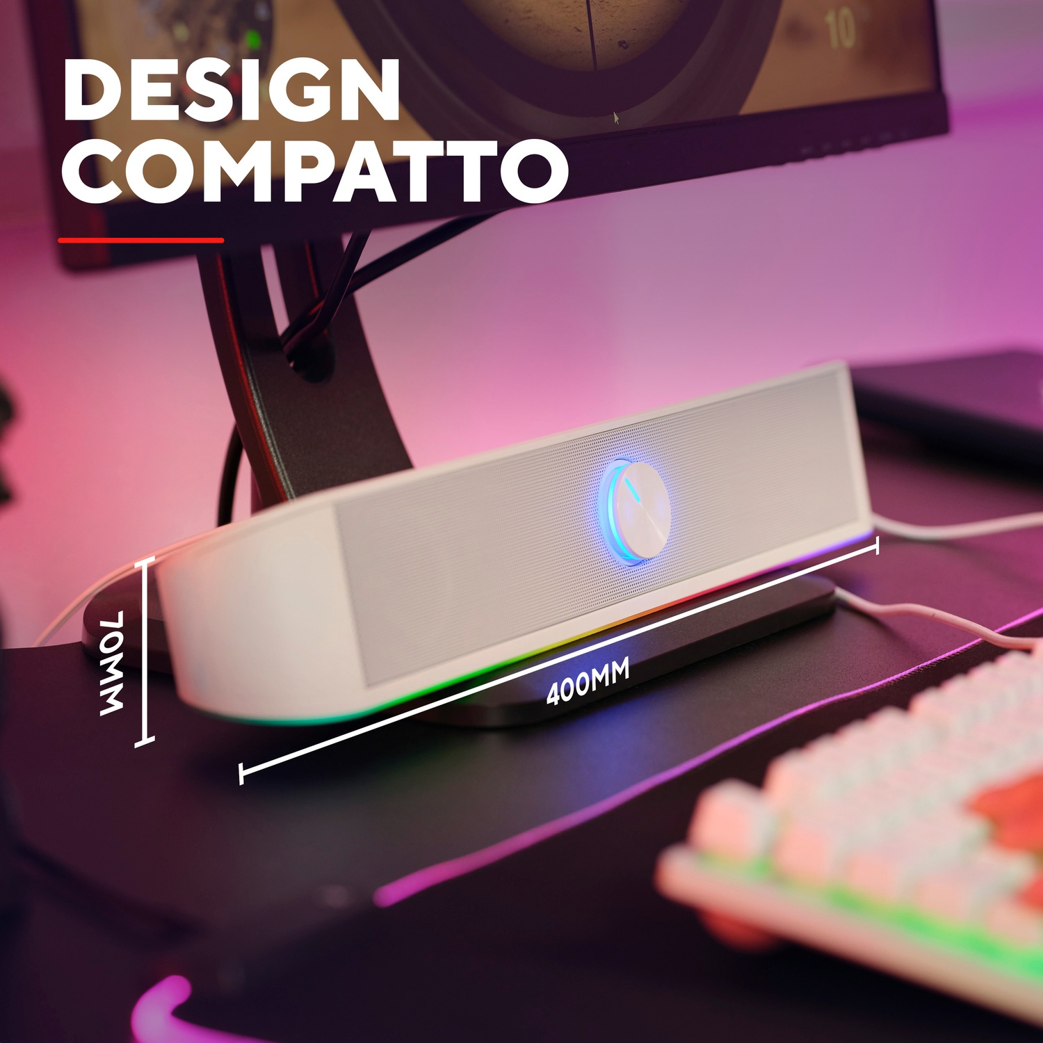 Una soundbar bianca con luce blu è su un pad nero. Tastiera e monitor sullo sfondo.