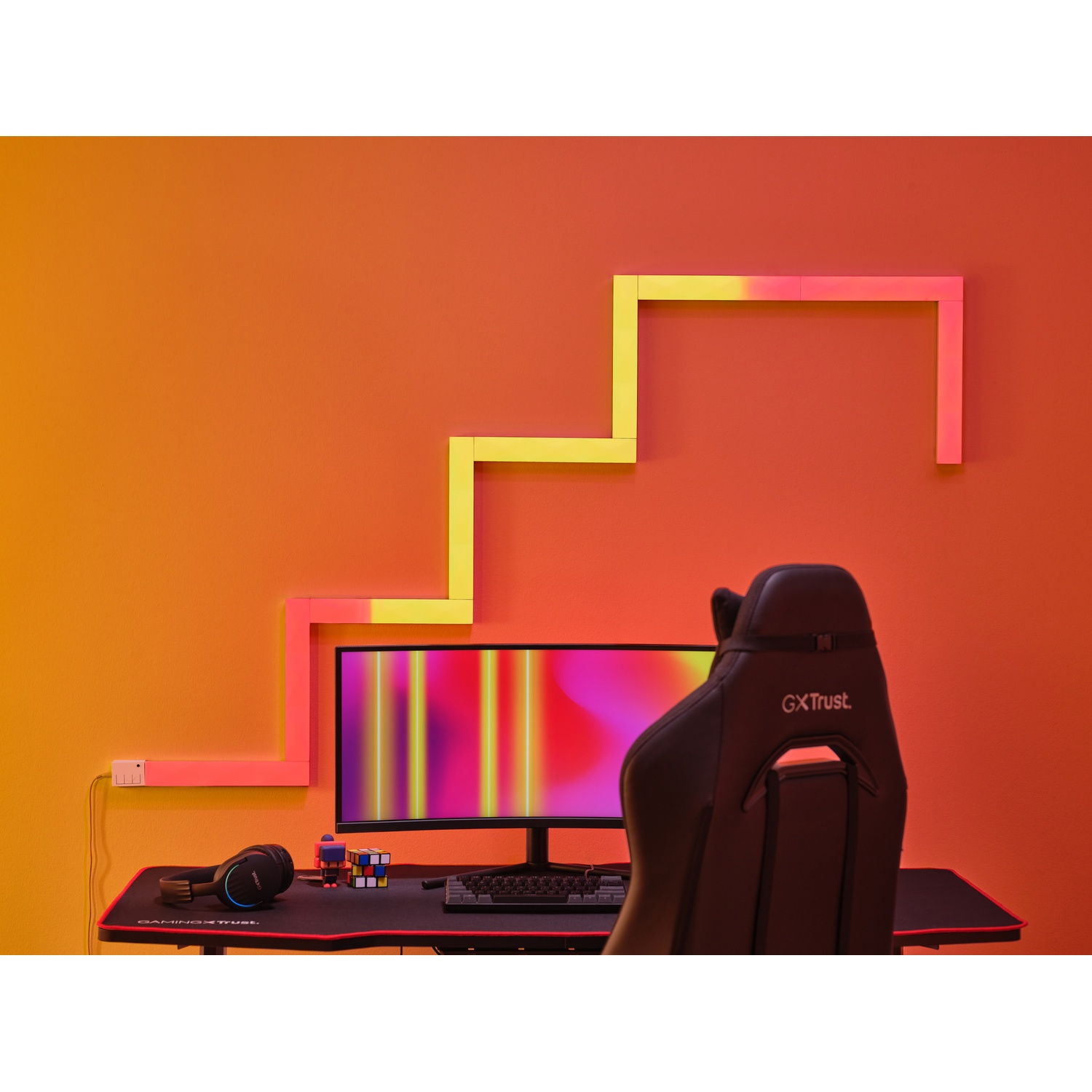 Configurazione di gioco moderna. Luci a LED a parete con motivo a scala. Sedia nera, scrivania, monitor e decorazioni.