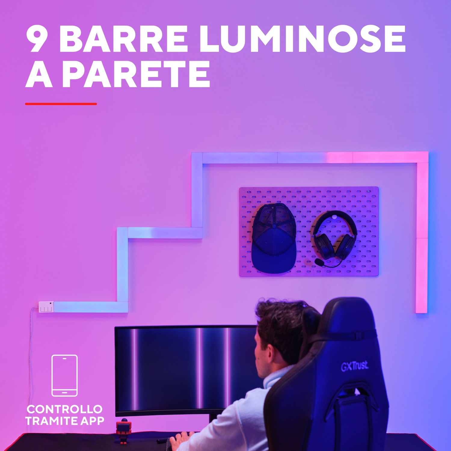 Un uomo seduto su una sedia da gioco guarda un monitor. Arte murale con luci e un cappello.