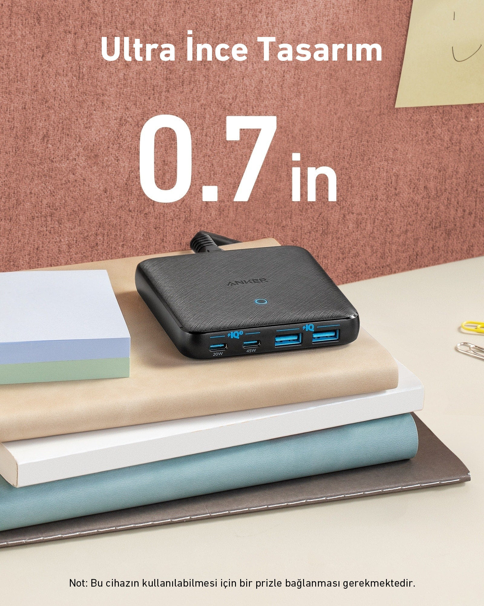 Çoklu USB portlu siyah bir Anker powerbank. Powerbank, bir yığın kitap ve kağıdın üzerinde duruyor.