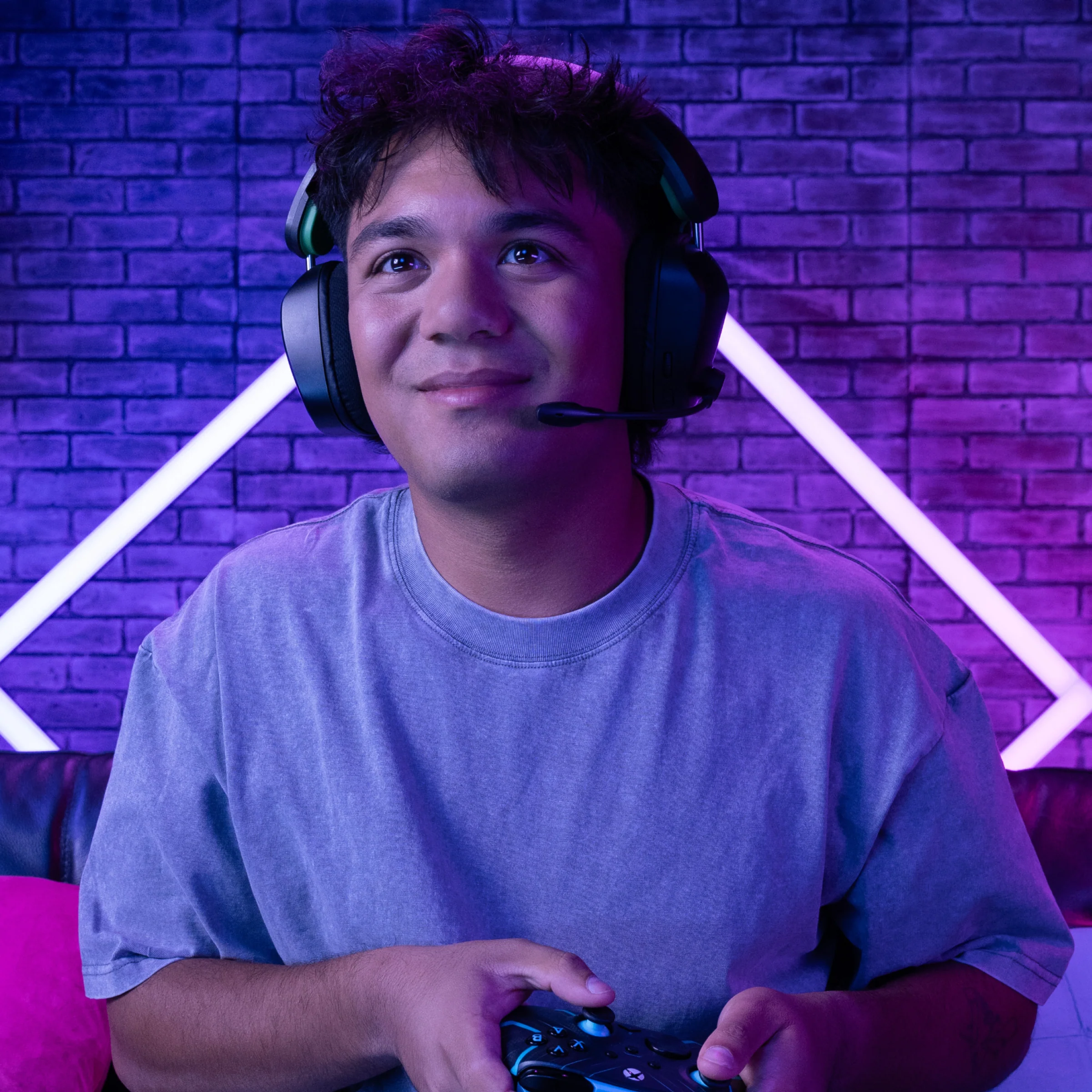 Ein junger Mann mit Headset und Controller, der beim Spielen eines Videospiels nach oben schaut.