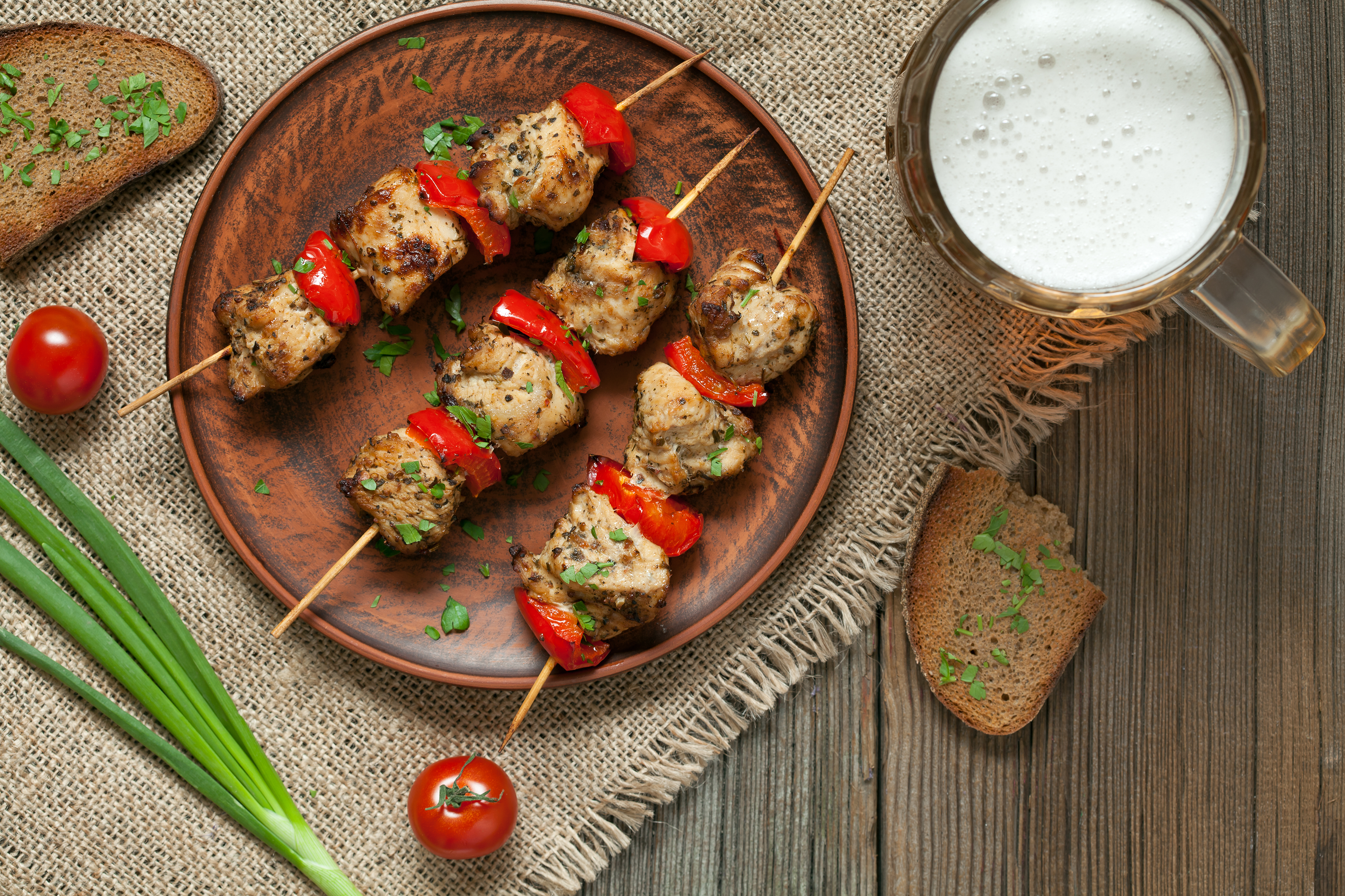 Vue aérienne de brochettes sur une assiette avec de la bière et du pain.