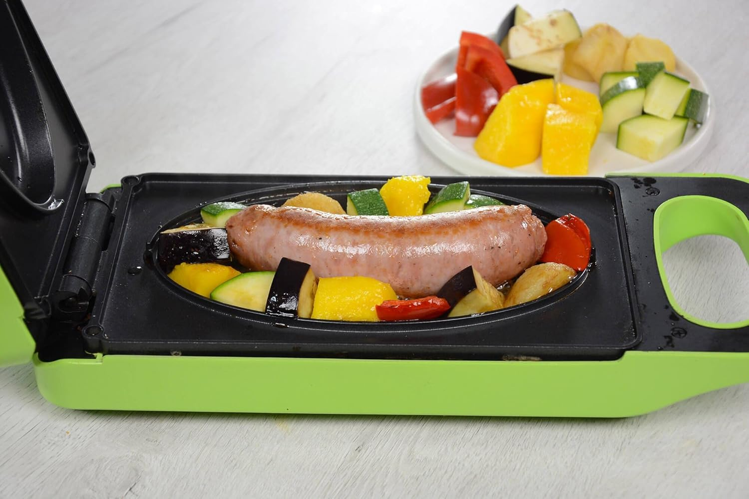 Piastra con salsiccia e verdure. Piatto di verdure sul retro.