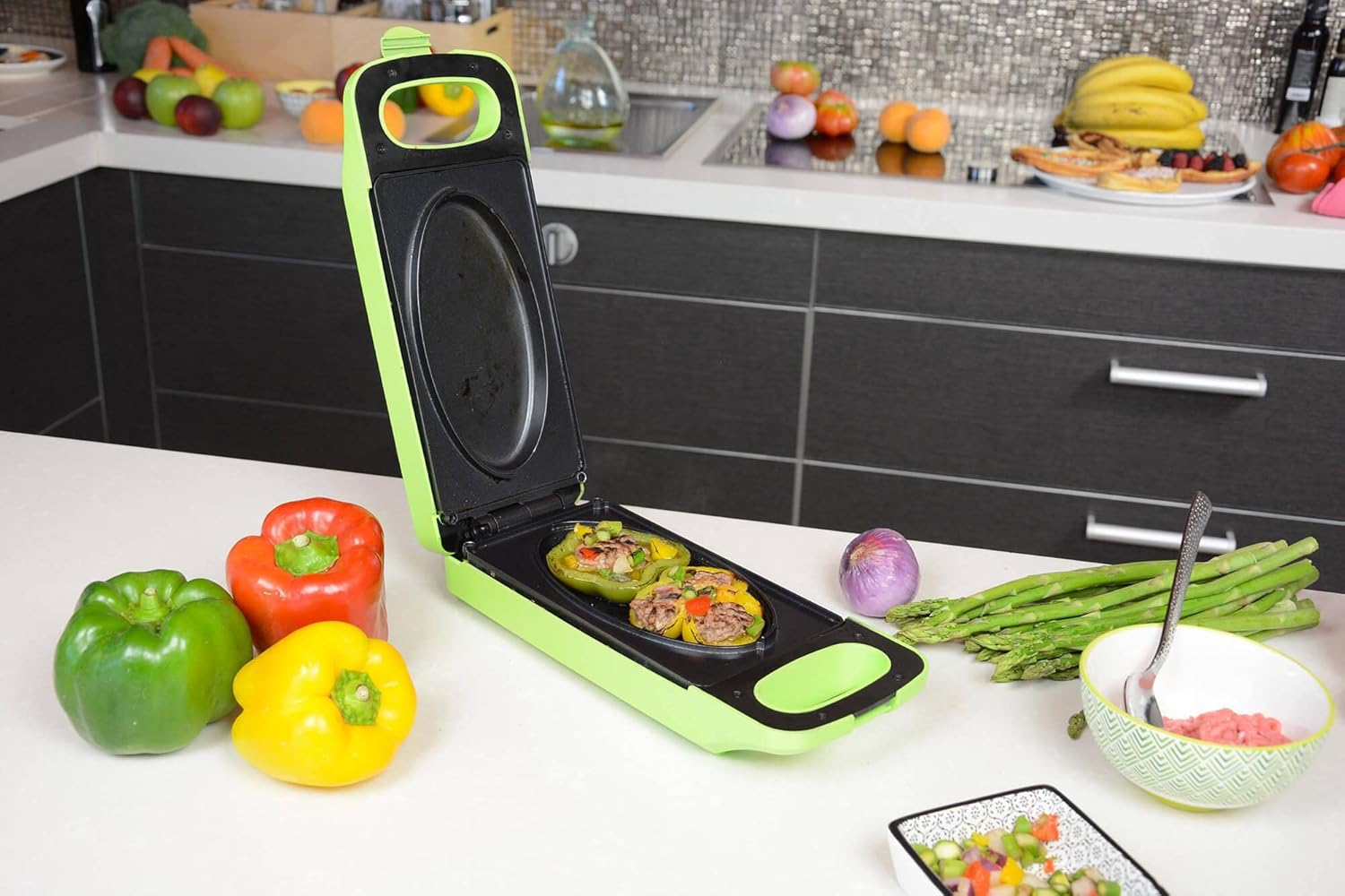 Peperoni verdi, rossi e gialli su un bancone bianco. Una griglia verde contiene peperoni ripieni. Frutta e verdura sullo sfondo.