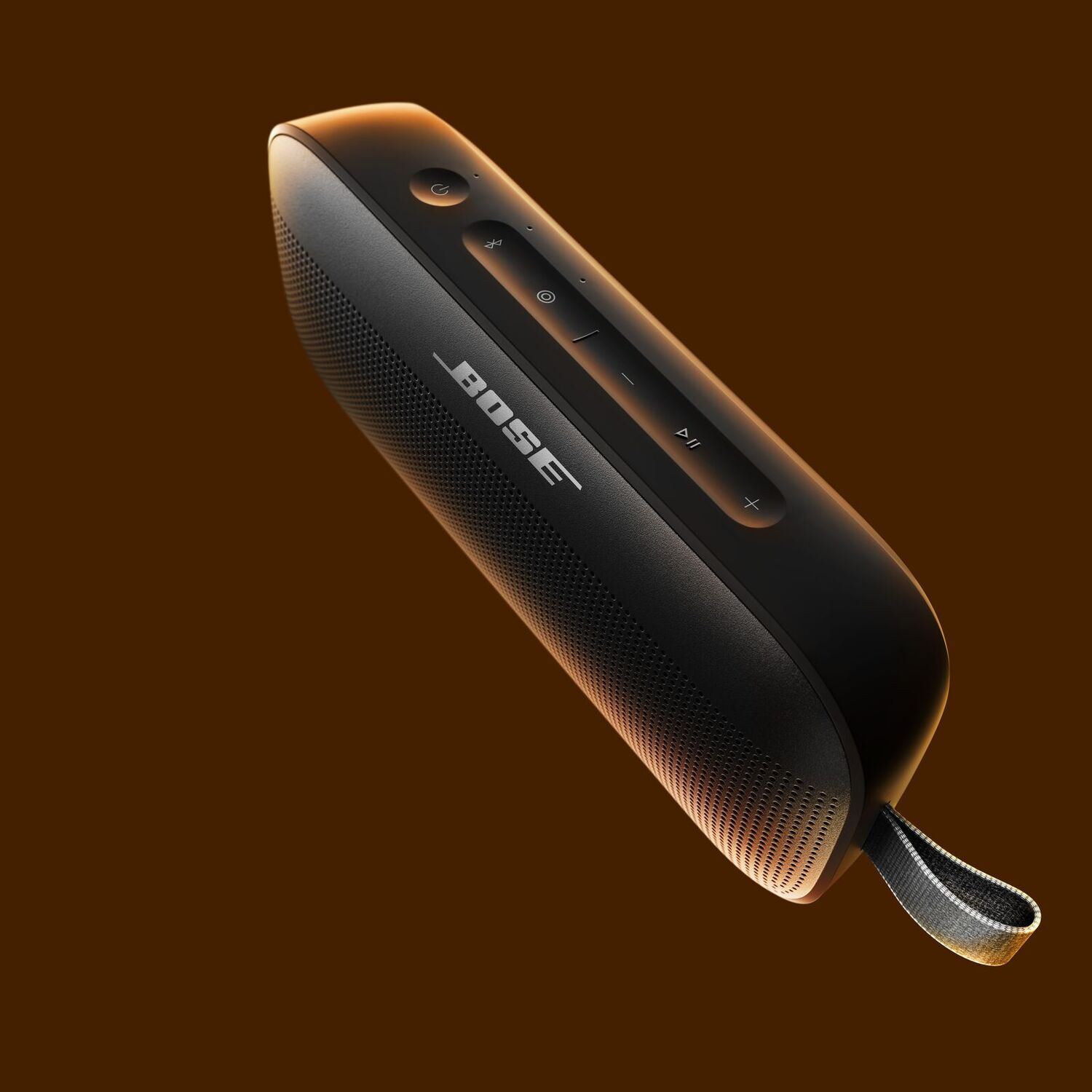 Une enceinte Bose noire avec une façade en mesh. Elle possède des boutons sur le dessus et une sangle grise sur le côté.