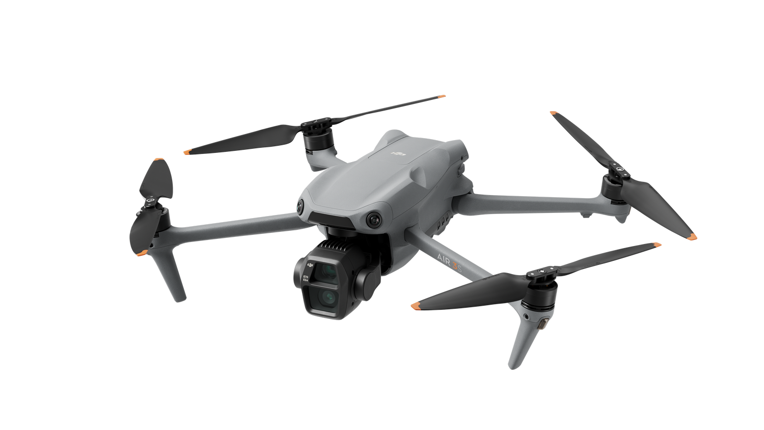 Un dron gris con cuatro hélices, mirando a la cámara, sobre un fondo negro. El dron está en el aire.