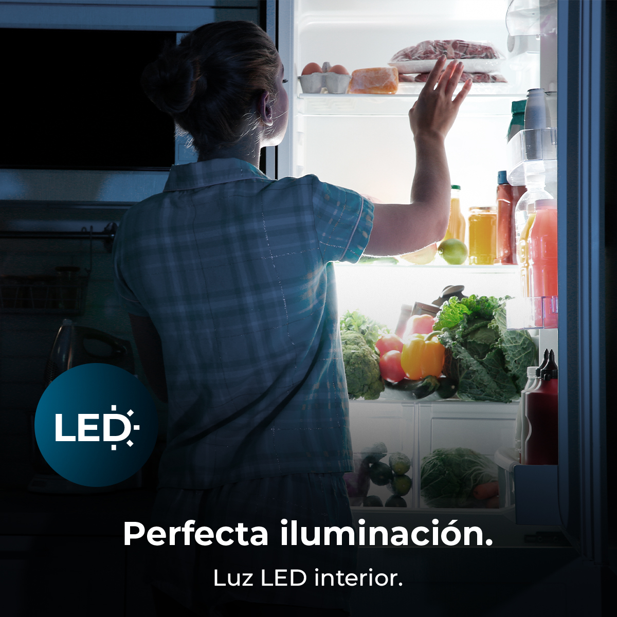 Una mujer abre un refrigerador con iluminación LED, revelando alimentos en su interior.