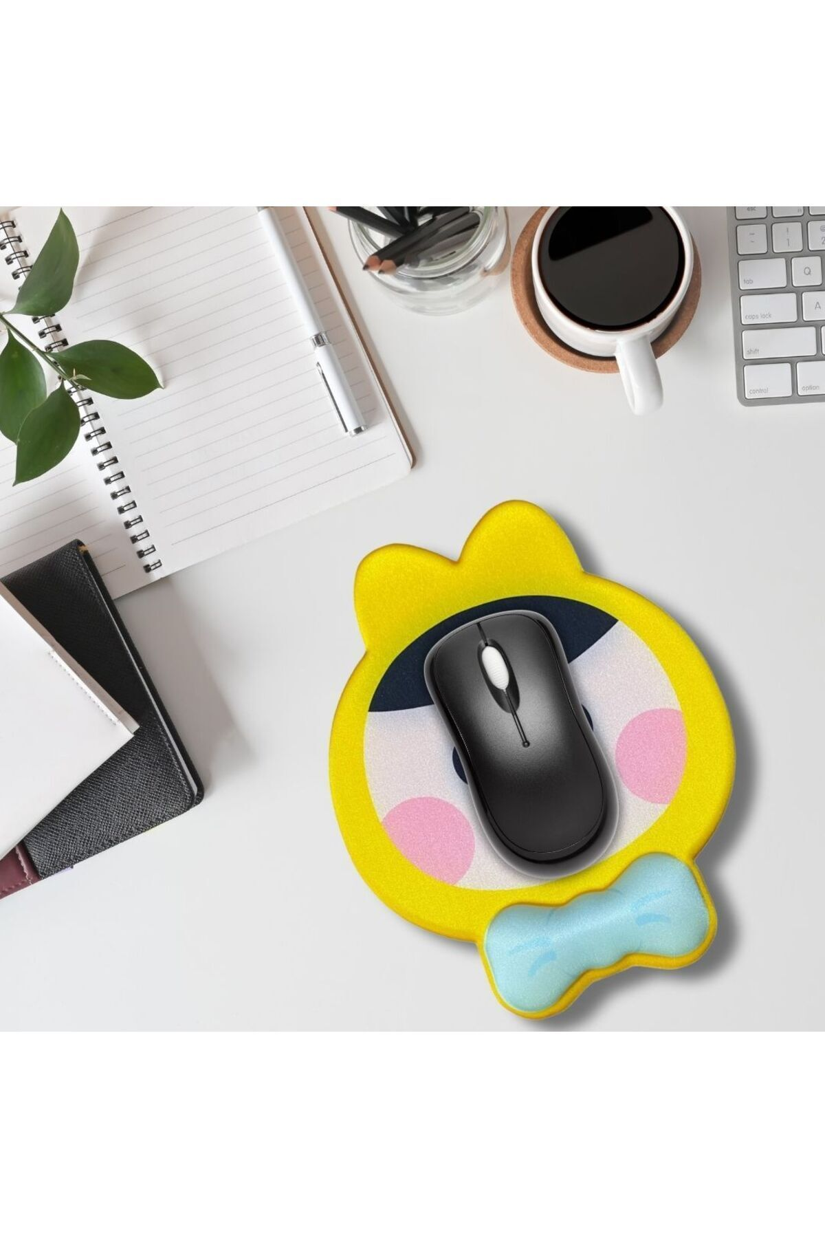 Çizgi film yüzü olan bir mousepad ve beyaz bir masada siyah bir fare.