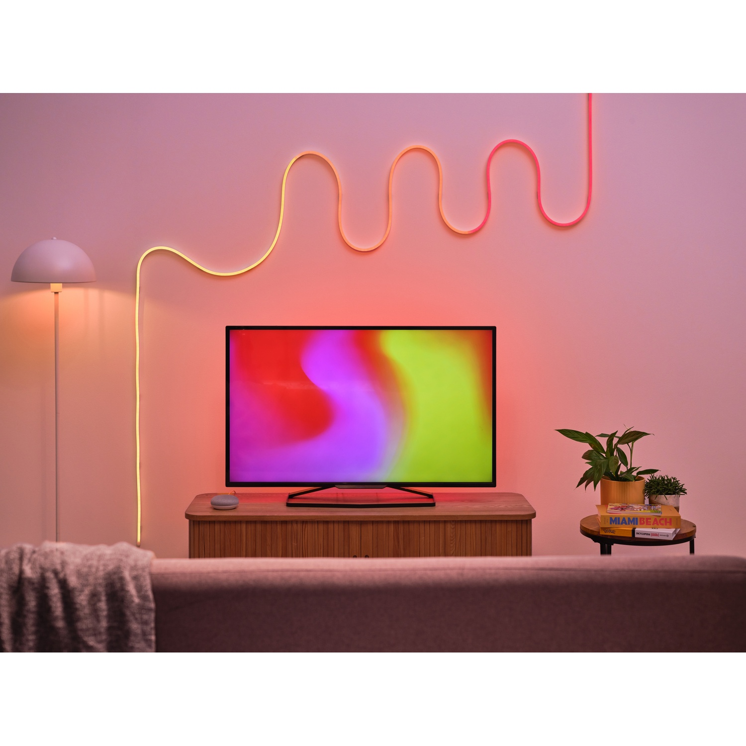 Scena di soggiorno con TV, luce al neon e divano. Lo schermo della TV mostra motivi colorati.