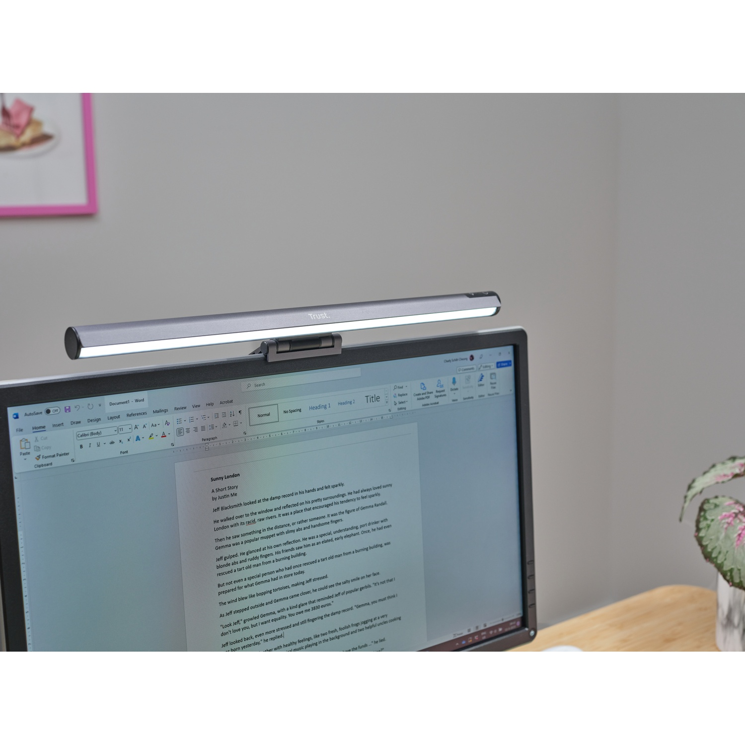 Uno schermo con testo è illuminato da una lampada da scrivania argentata. Un documento rosa è a sinistra.