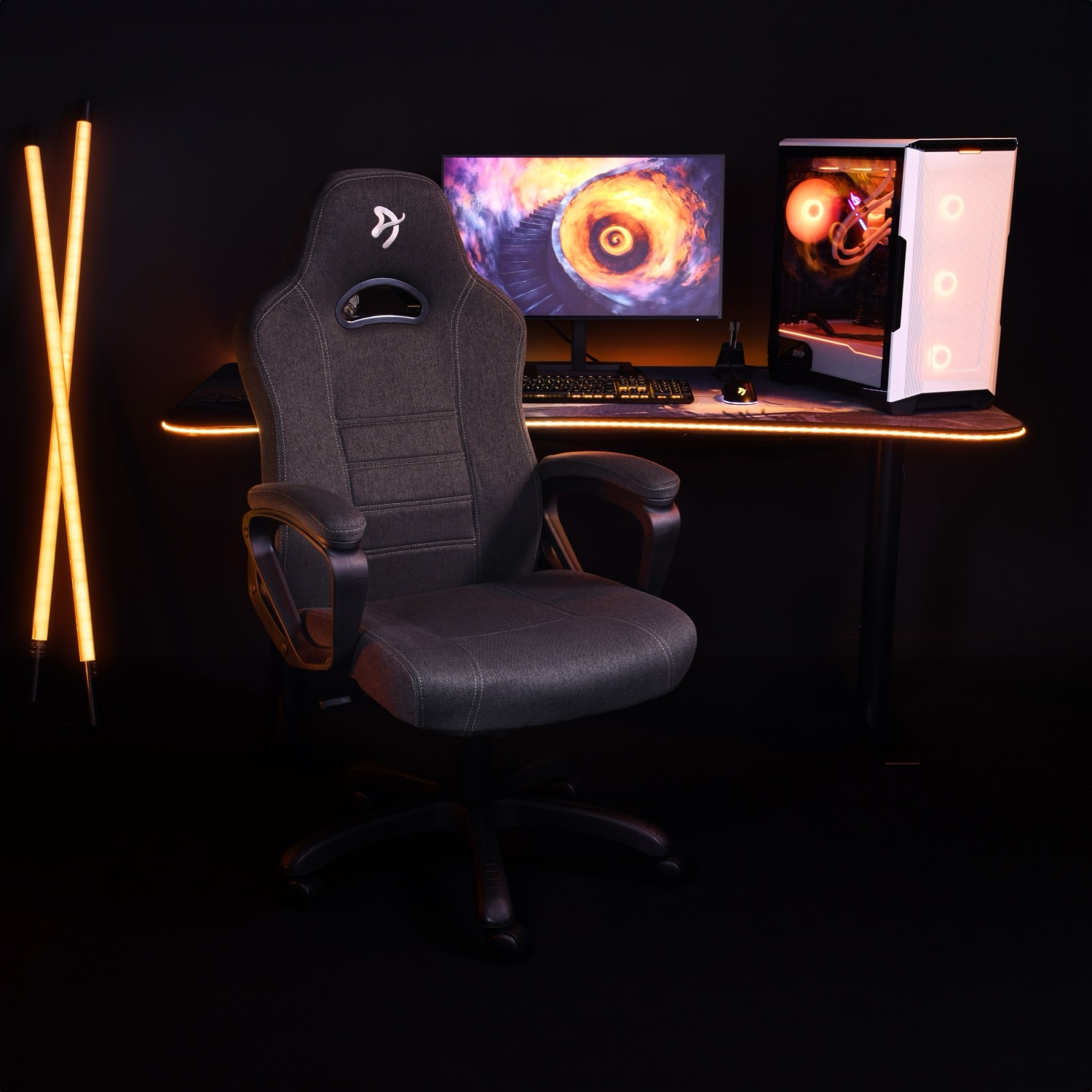 Ein Gaming-Setup mit Gaming-Stuhl, Monitor, Tastatur und Computergehäuse mit Lichtern.
