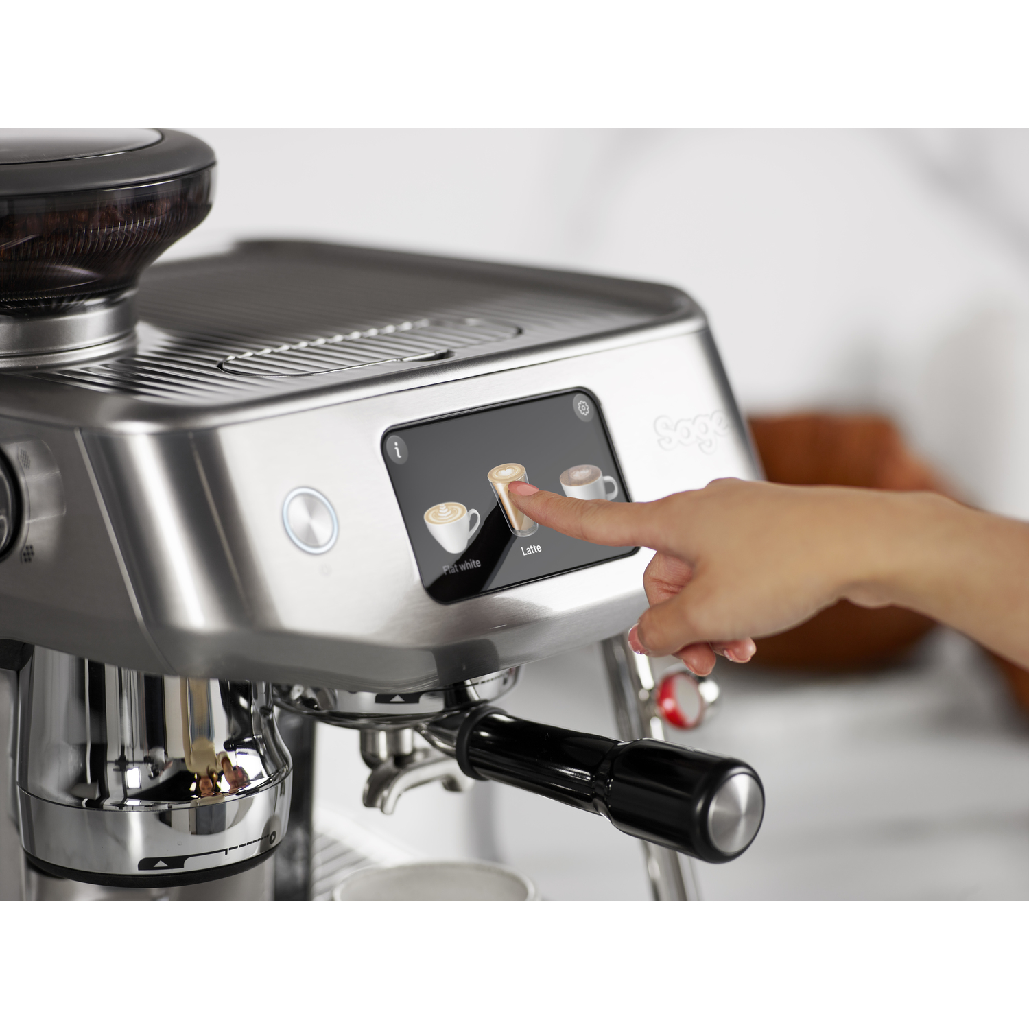 Machine à expresso avec un doigt touchant le bouton 'Latte' sur un écran.