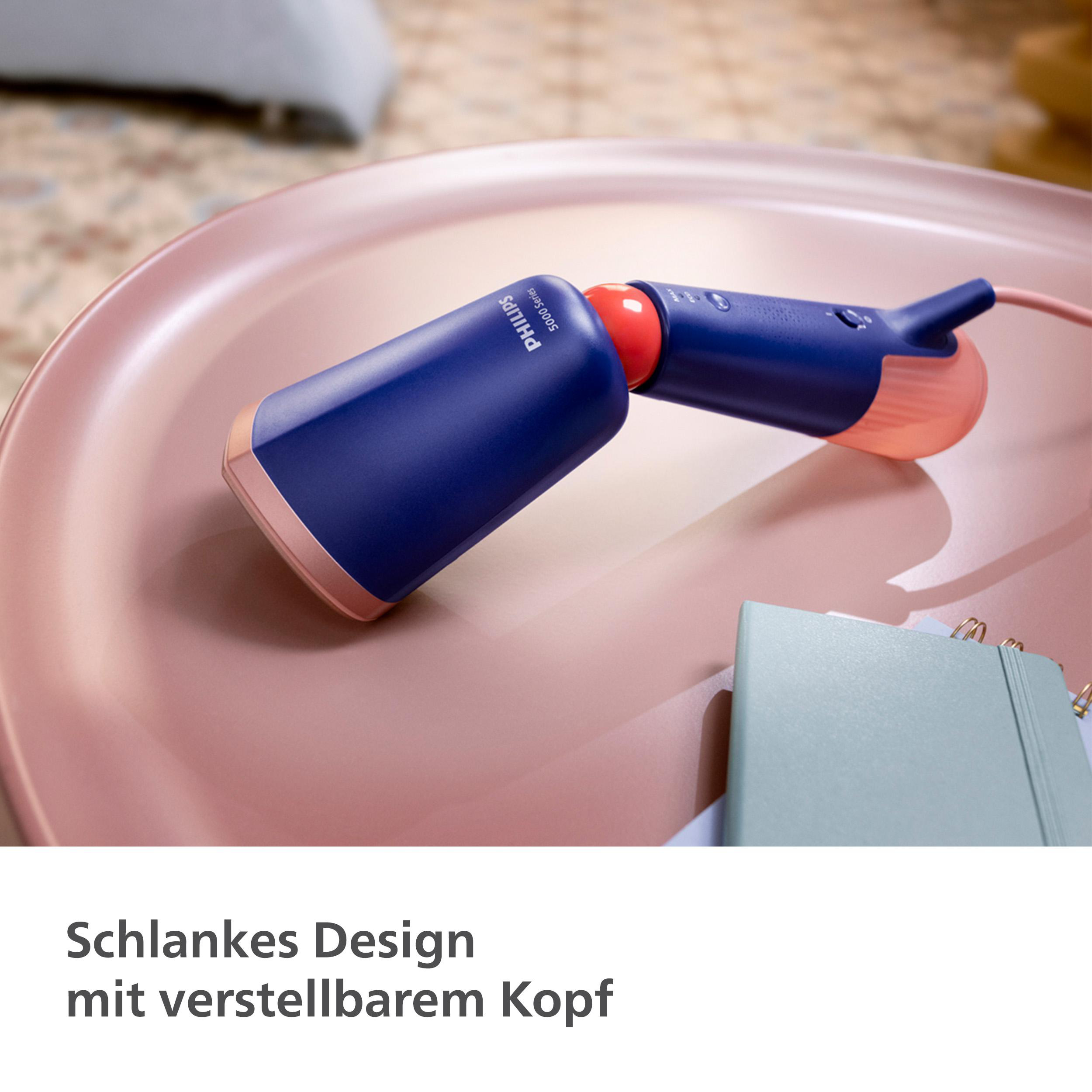 Ein Philips-Dampfgarer auf einem blauen Tisch mit Zeitschrift, Schal und rotem Objekt.