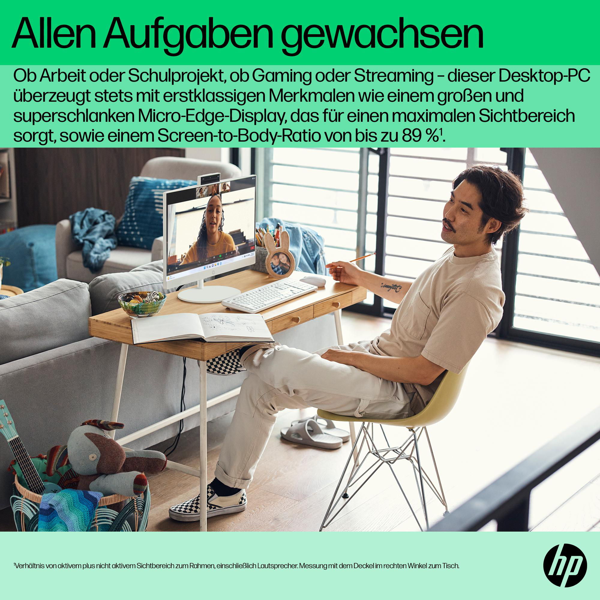 Mann sitzt an einem Schreibtisch mit Computer, Notizbuch und verschiedenen Gegenständen im Wohnzimmer.