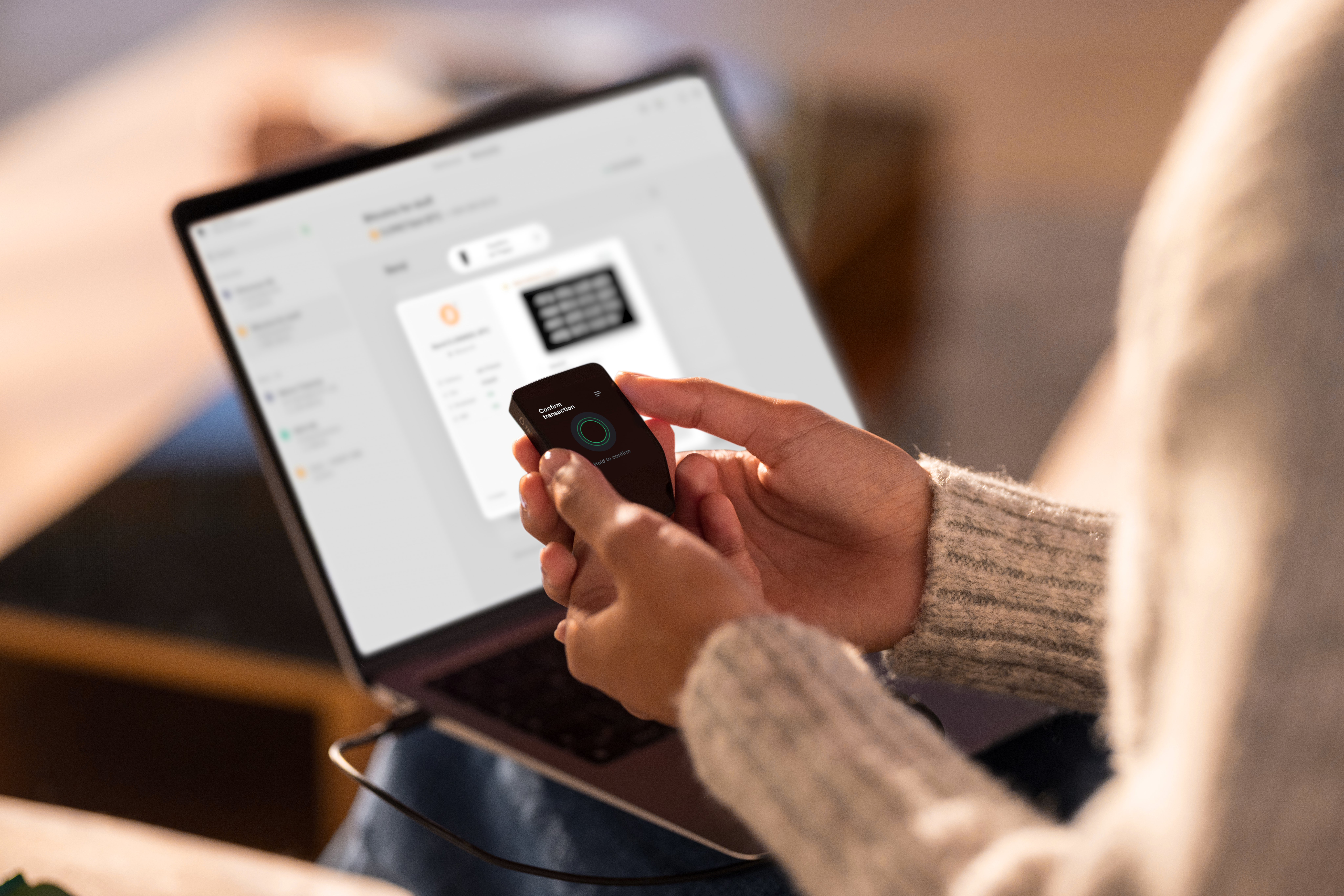 Person verwendet Laptop mit angeschlossenem Ledger Hardware Wallet.