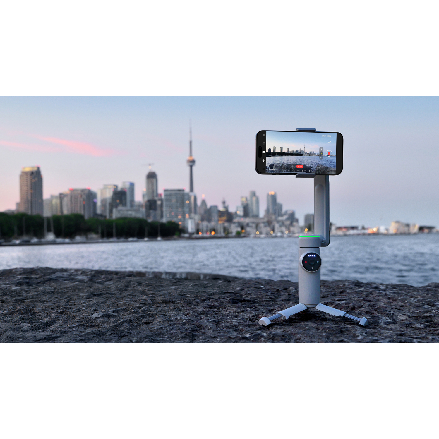 A phone mounted on a stabilizer, with a city skyline in the background.