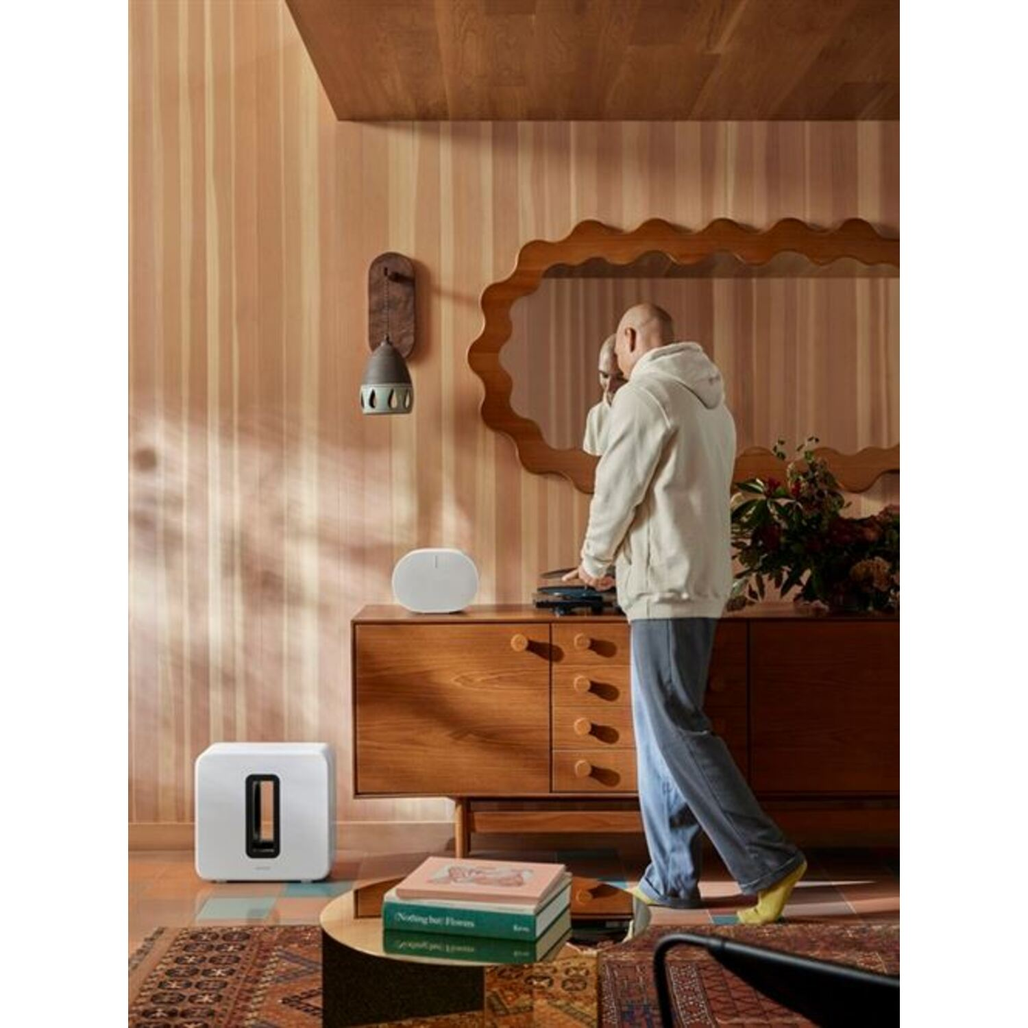 A man is standing near a white sound system next to a cabinet.